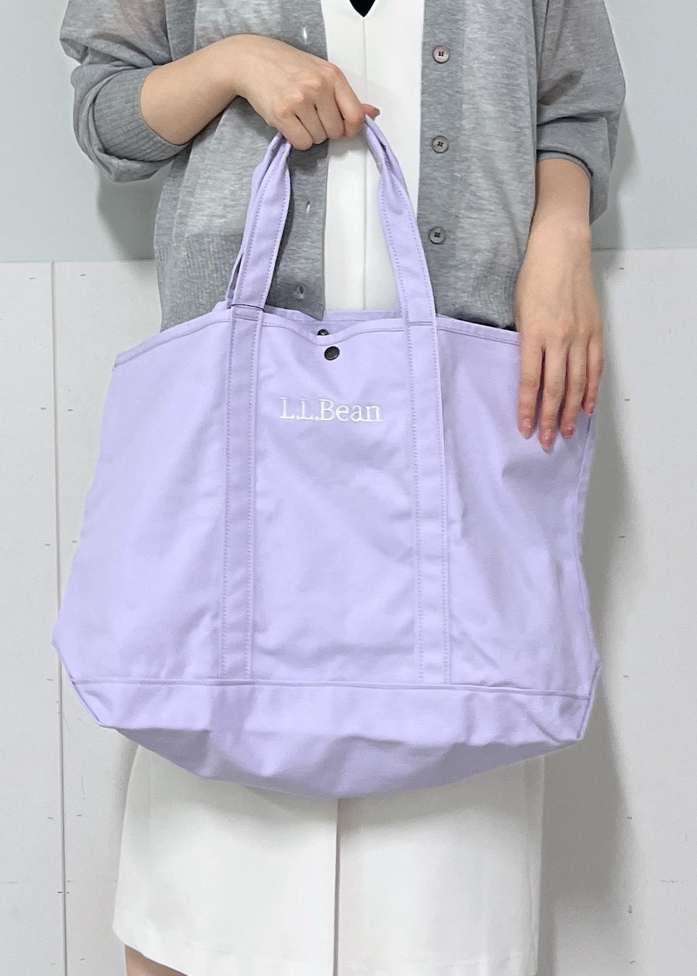 シルバー系のカーディガン/ボレロ、ホワイト系のジャンパースカート、パープル系のトートバッグを着用したレディースの夏コーディネートの6枚目の写真