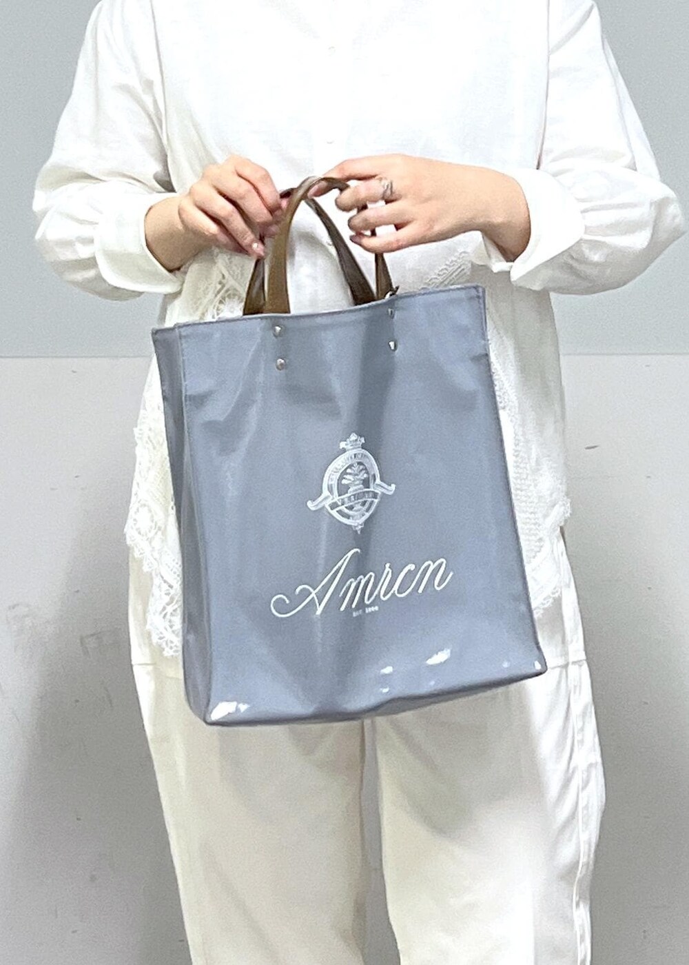 ブルー系のトートバッグ、ホワイト系のシャツ/ブラウス、ベージュ系のニット/セーターを着用したレディースの冬コーディネートの9枚目の写真