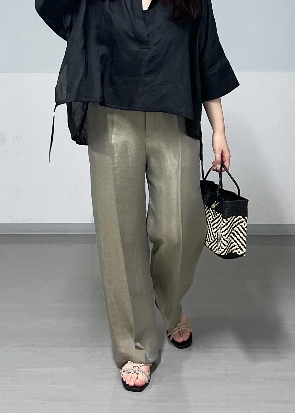 ブラック系のかごバッグ、ゴールド系のサンダル、グレー系のその他パンツを着用したレディースの春コーディネートの6枚目の写真