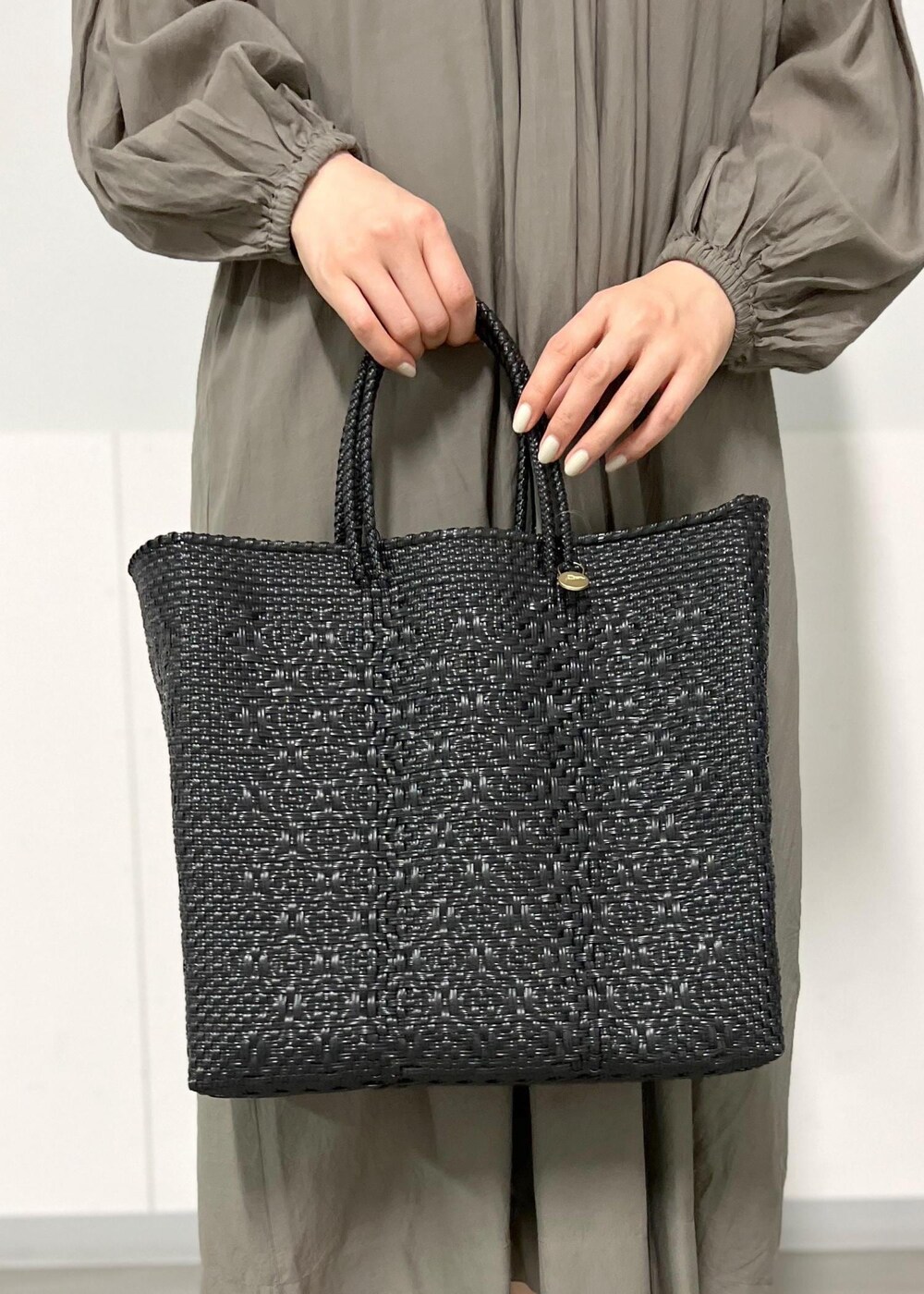 ブラック系のサンダル、グレー系のワンピース、ブラック系のかごバッグを着用したレディースの春コーディネートの8枚目の写真