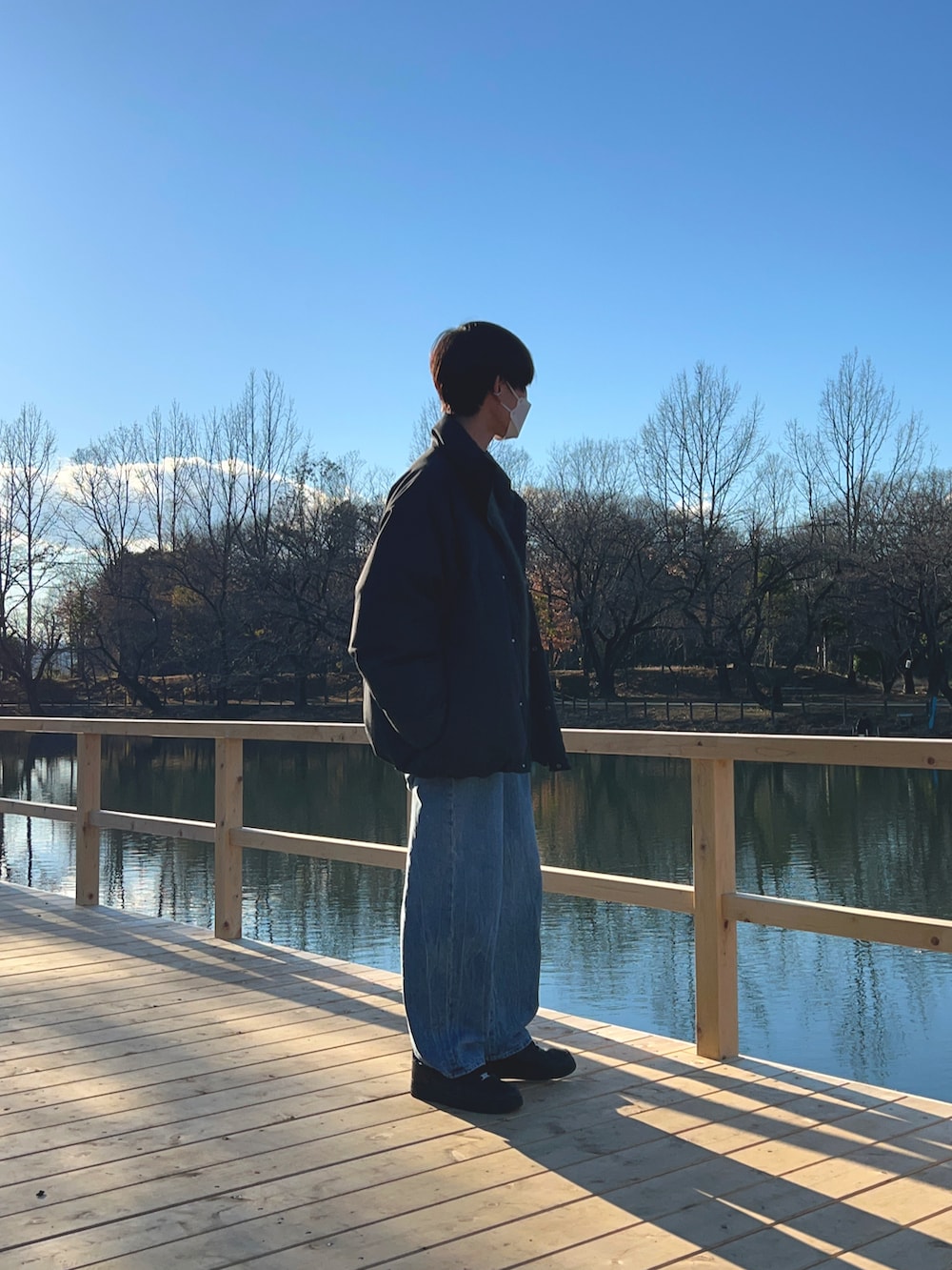 グレー系のダウンジャケット/コート、グリーン系のニット/セーター、ブルー系のデニムパンツを着用したメンズの夏コーディネートの5枚目の写真