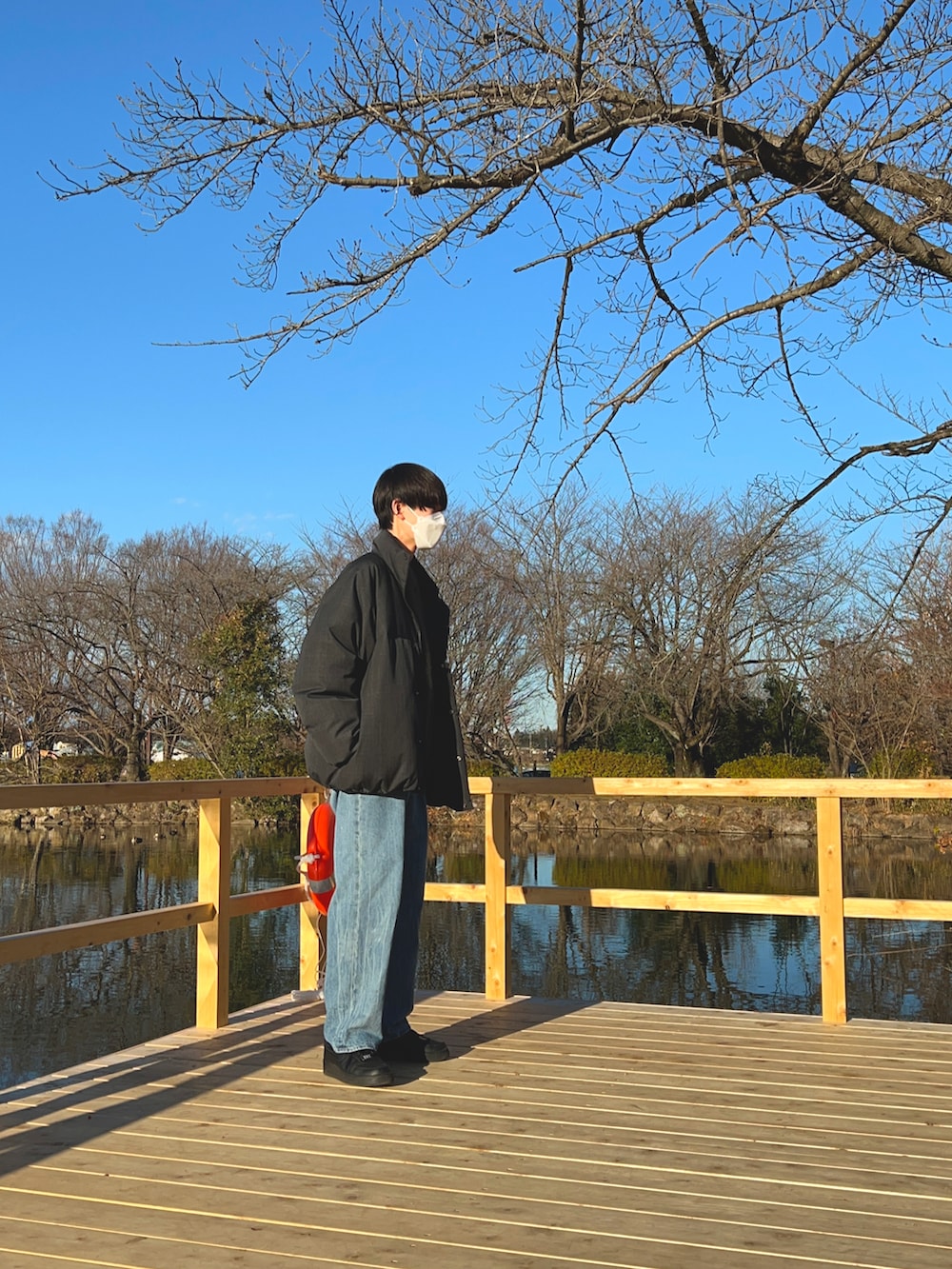 グレー系のダウンジャケット/コート、グリーン系のニット/セーター、ブルー系のデニムパンツを着用したメンズの夏コーディネートの3枚目の写真