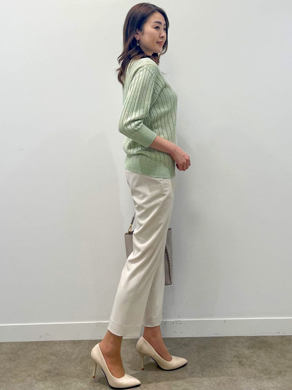 ベージュ系のスーツパンツ、グレー系のショルダーバッグ、グリーン系のニット/セーターを着用したレディースの春コーディネートの5枚目の写真