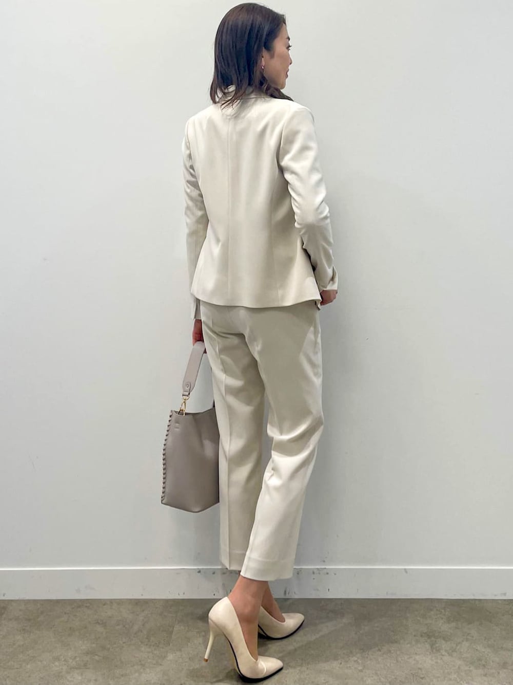 ベージュ系のスーツパンツ、グレー系のショルダーバッグ、グリーン系のニット/セーターを着用したレディースの春コーディネートの3枚目の写真