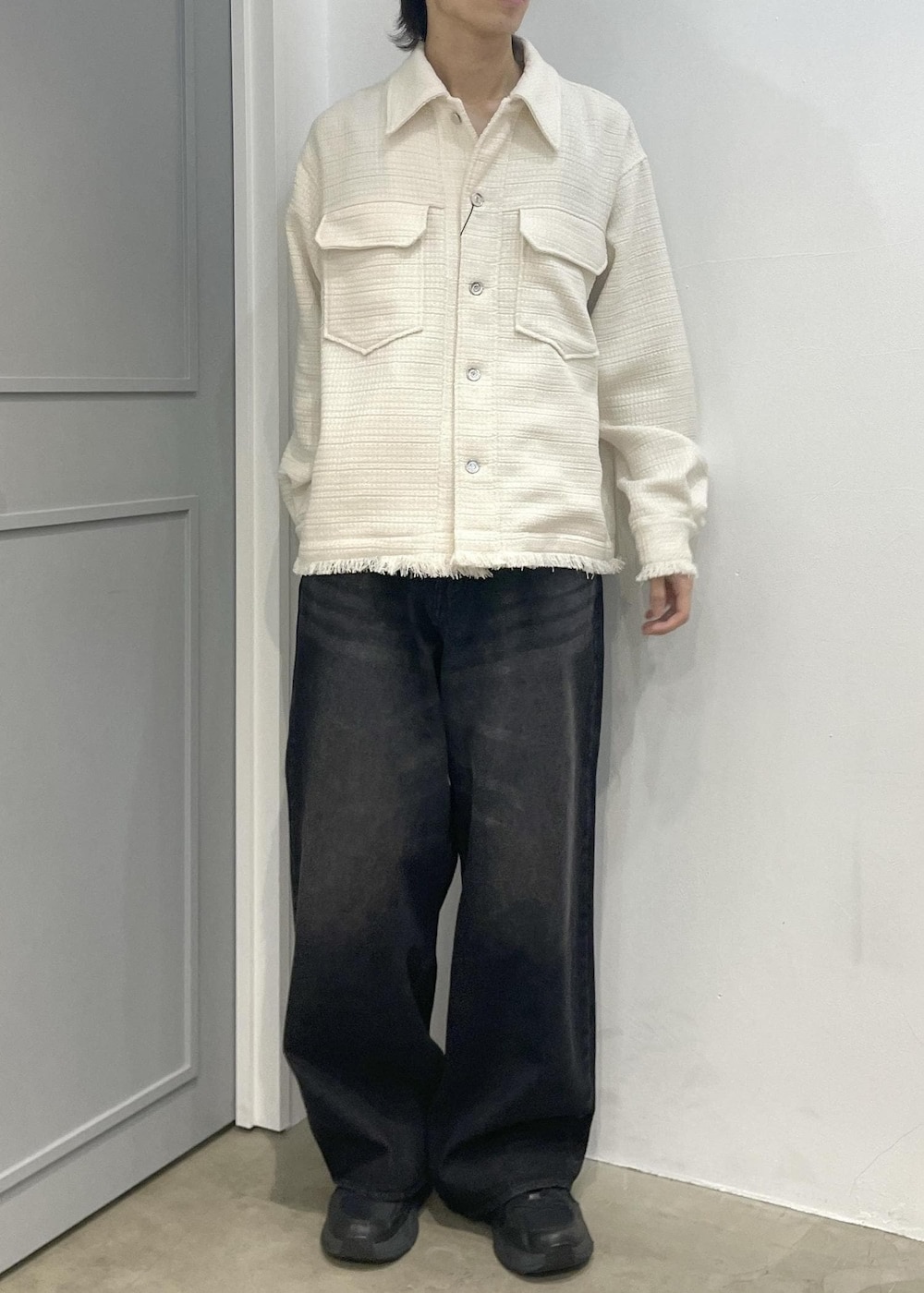 ブラック系のデニムパンツ、ホワイト系のブルゾンを着用したメンズの春コーディネートの2枚目の写真