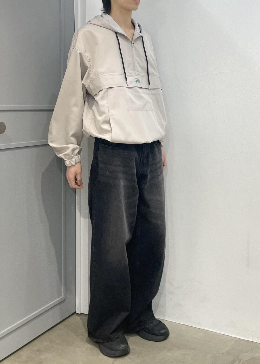 ブラック系のデニムパンツ、ベージュ系のブルゾンを着用したメンズの春コーディネートの2枚目の写真