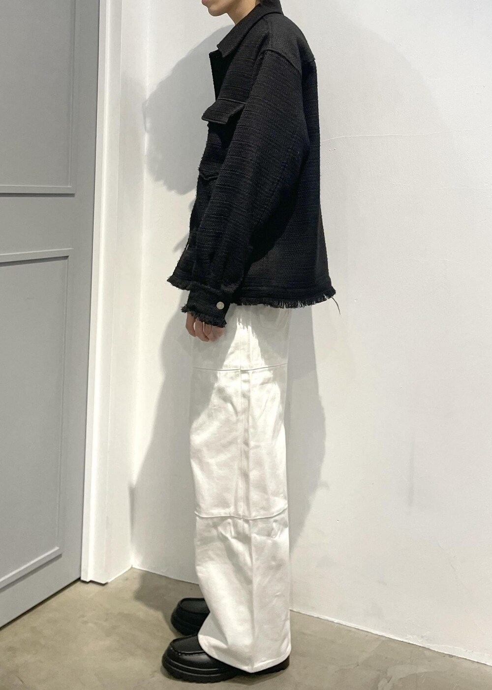 ブラック系のローファー、ホワイト系のカーゴパンツ、ブラック系のブルゾンを着用したメンズの春コーディネートの3枚目の写真