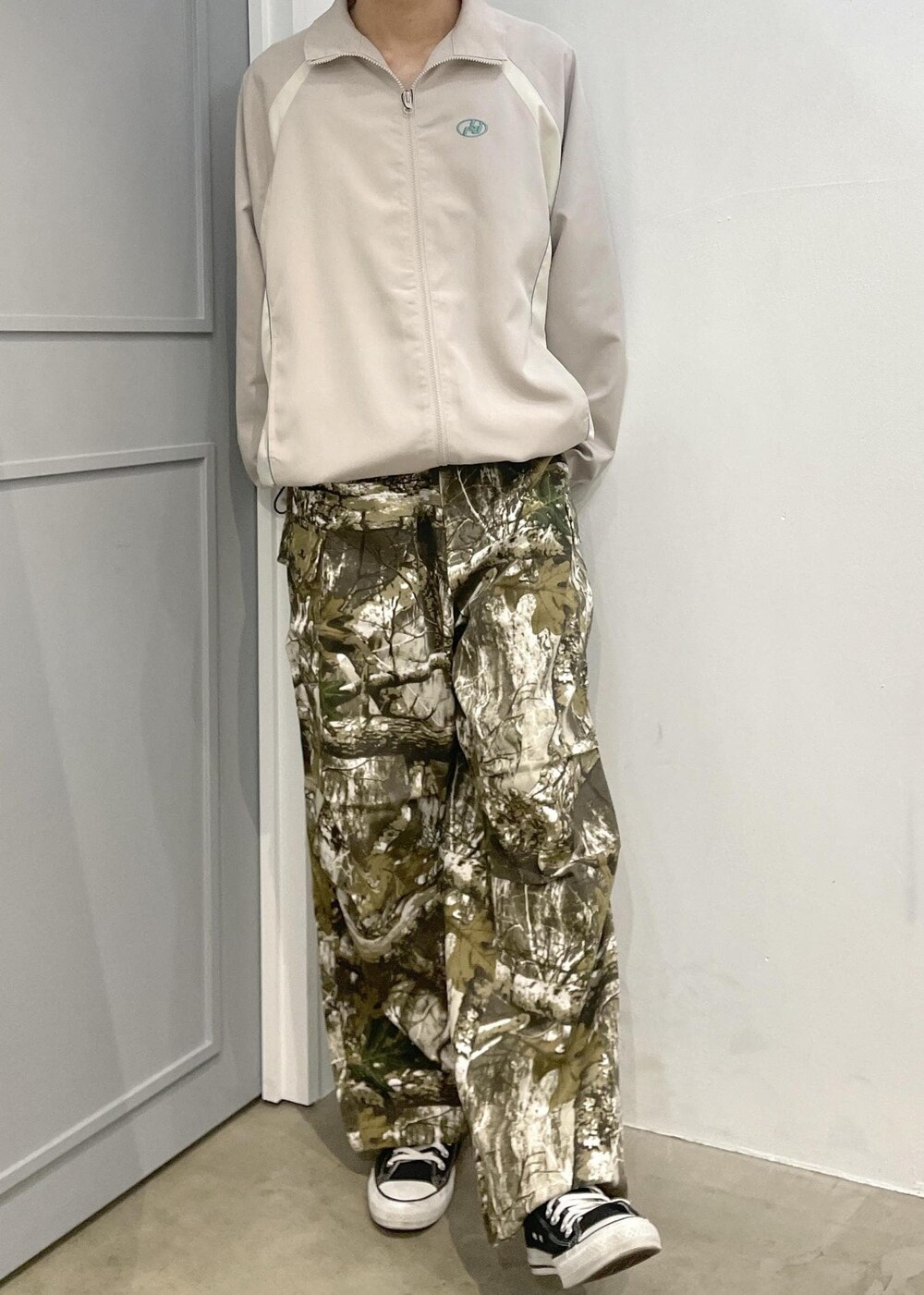 グリーン系のカーゴパンツ、ベージュ系のナイロンジャケットを着用したメンズの春コーディネートの2枚目の写真