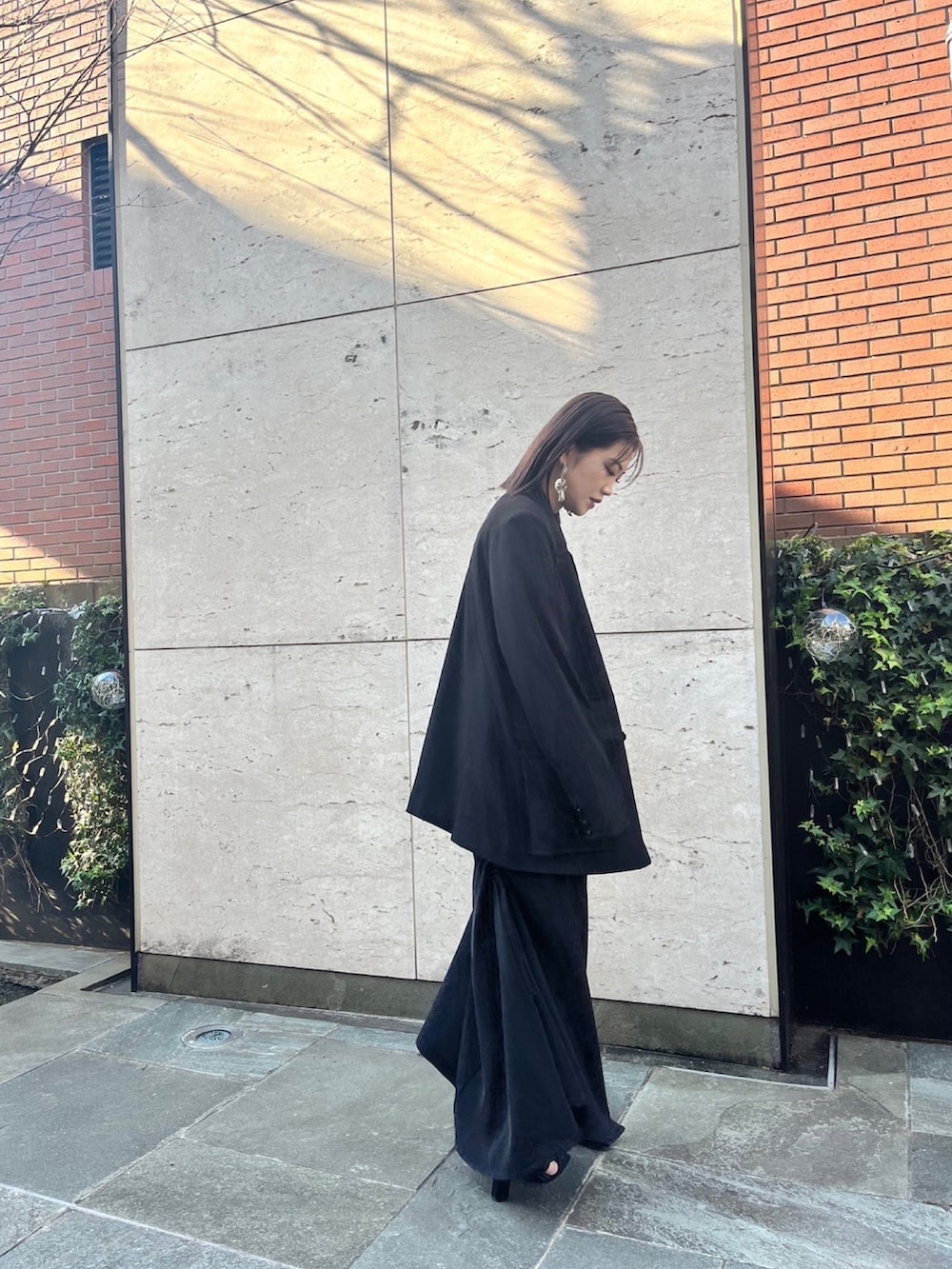 ブラック系のスカート、ブラック系のパンプス、ブラック系のテーラードジャケットを着用したレディースの冬コーディネートの2枚目の写真