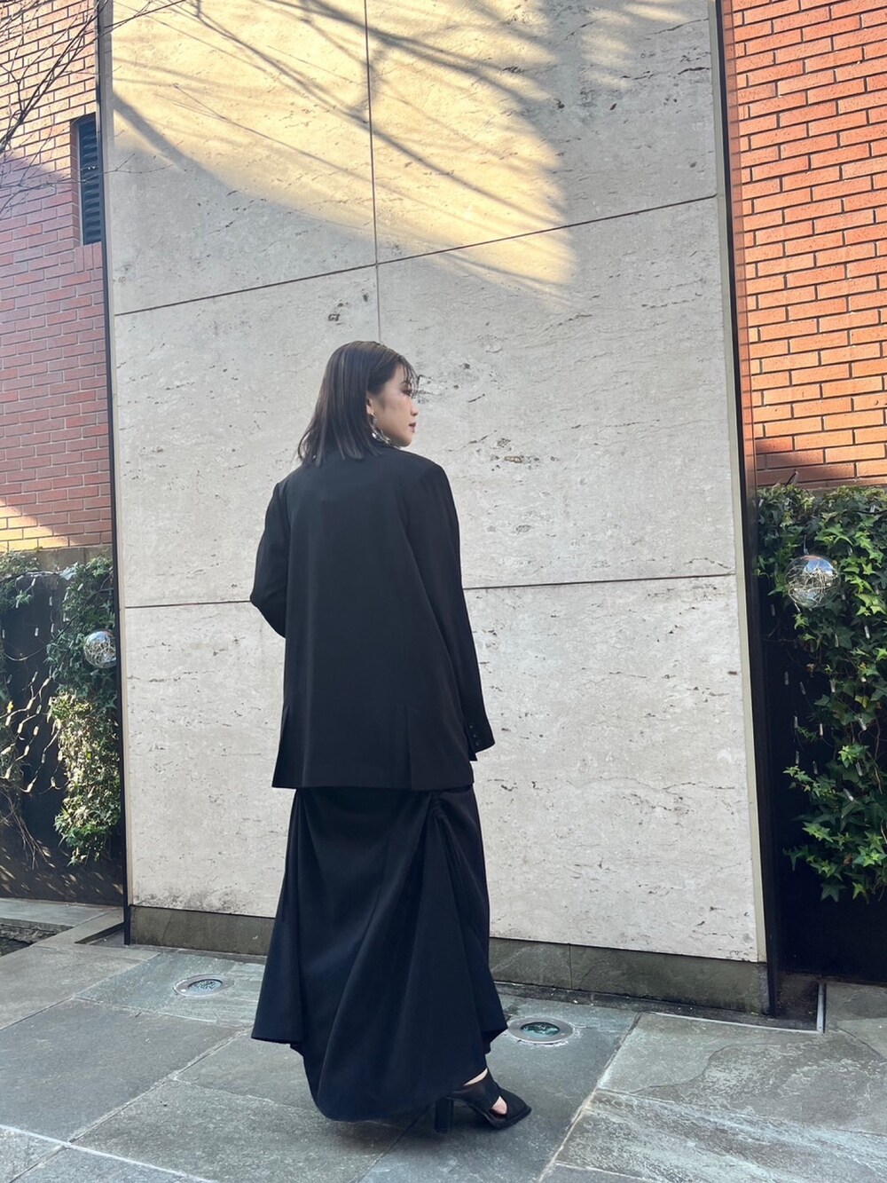 ブラック系のスカート、ブラック系のパンプス、ブラック系のテーラードジャケットを着用したレディースの冬コーディネートの3枚目の写真