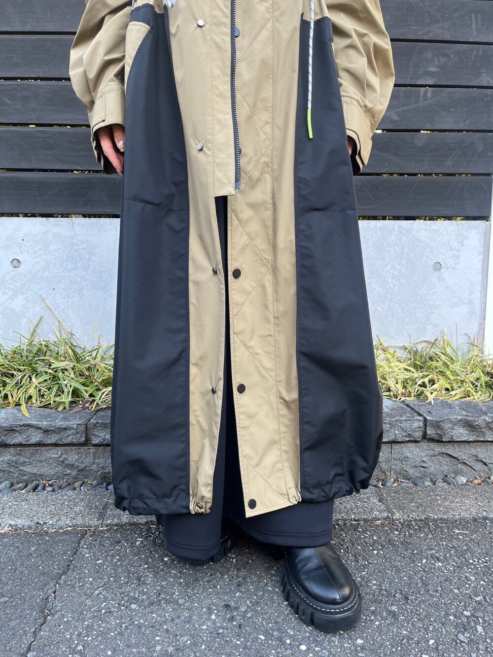 ベージュ系のマウンテンパーカー、ブラック系のワンピース、シルバー系のイヤリングを着用したレディースの冬コーディネートの7枚目の写真