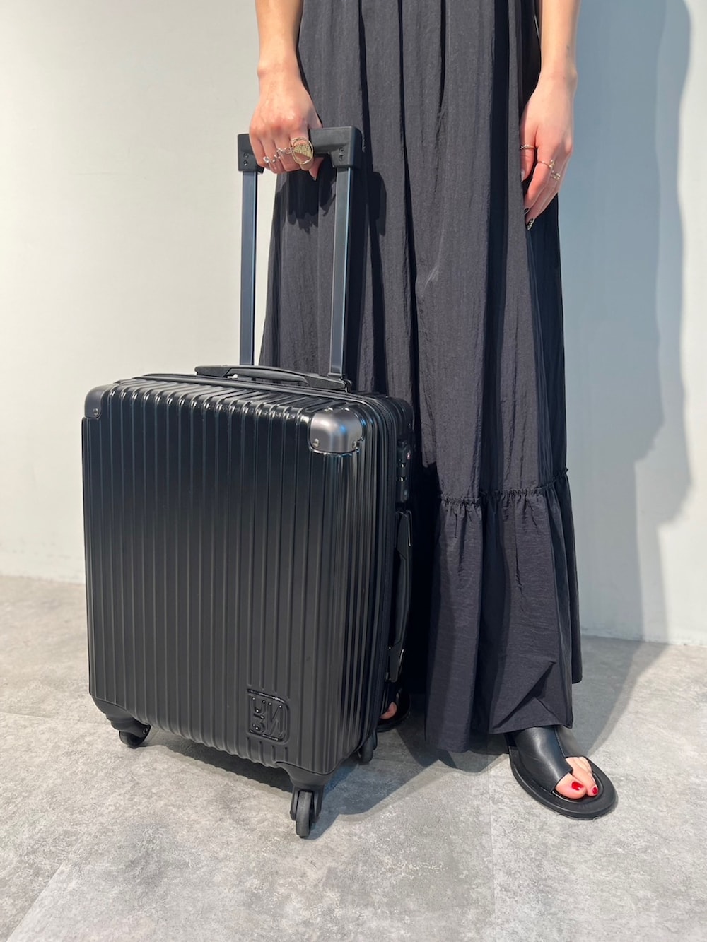 レッド系のタンクトップ、ブラック系のサンダル、ブラック系のスーツケース/キャリーバッグを着用したレディースの春コーディネートの7枚目の写真