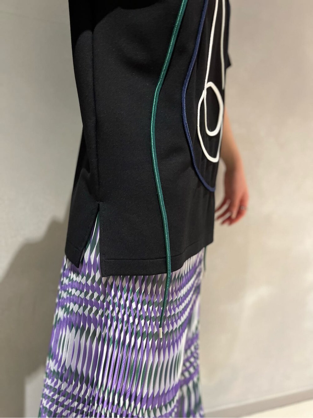 パープル系のスカート、ブラック系のTシャツ/カットソー、ブラック系のサンダルを着用したレディースの夏コーディネートの5枚目の写真