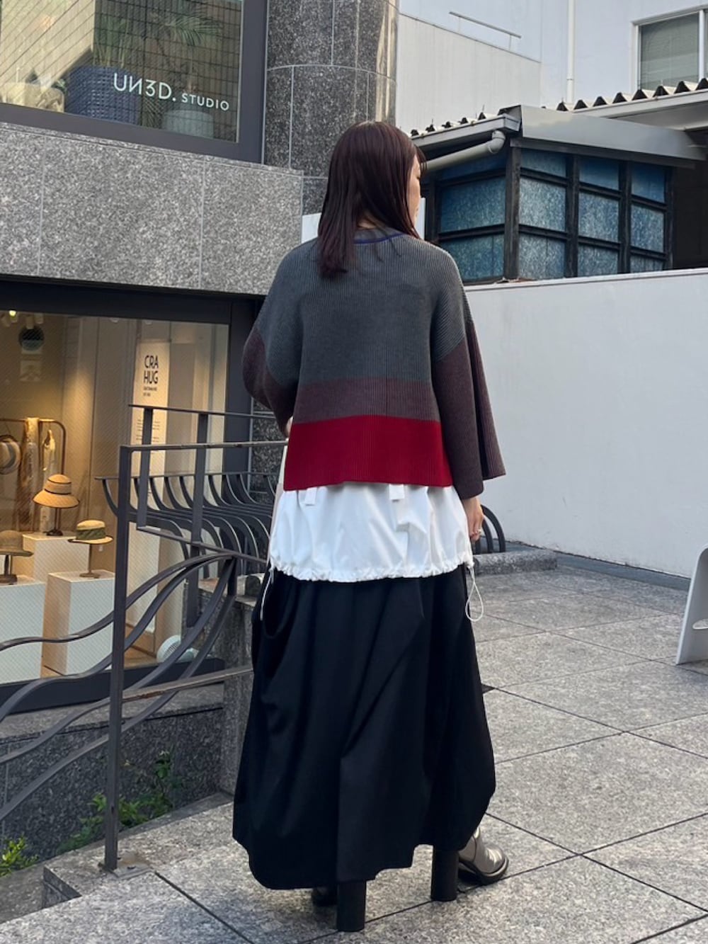 グレー系のニット/セーター、ホワイト系のシャツ/ブラウス、シルバー系のパンプスを着用したレディースの夏コーディネートの2枚目の写真