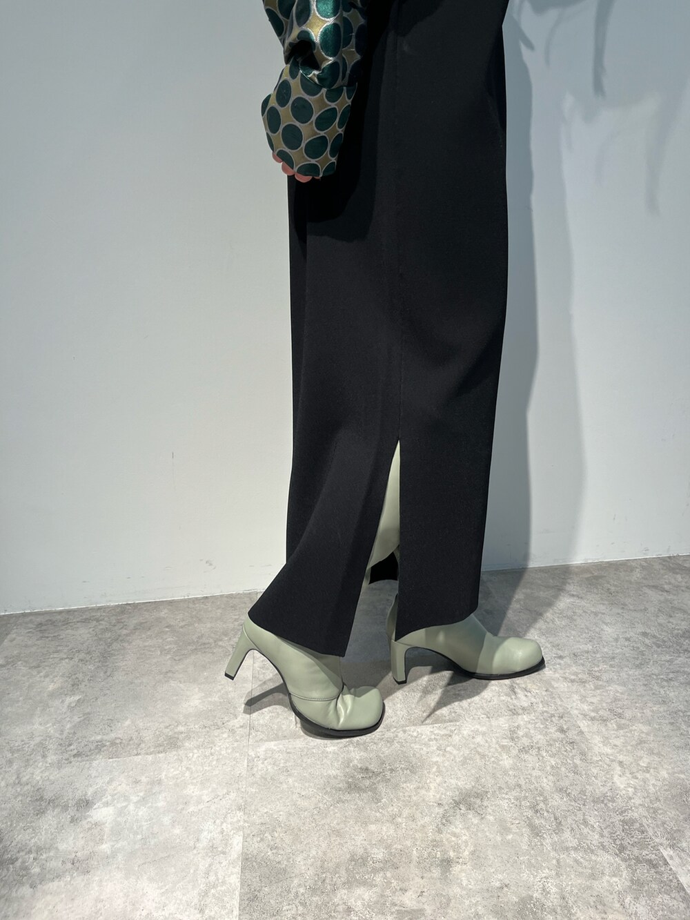 グリーン系のブルゾン、ブラック系のワンピース、グレー系のブーツを着用したレディースの秋コーディネートの5枚目の写真