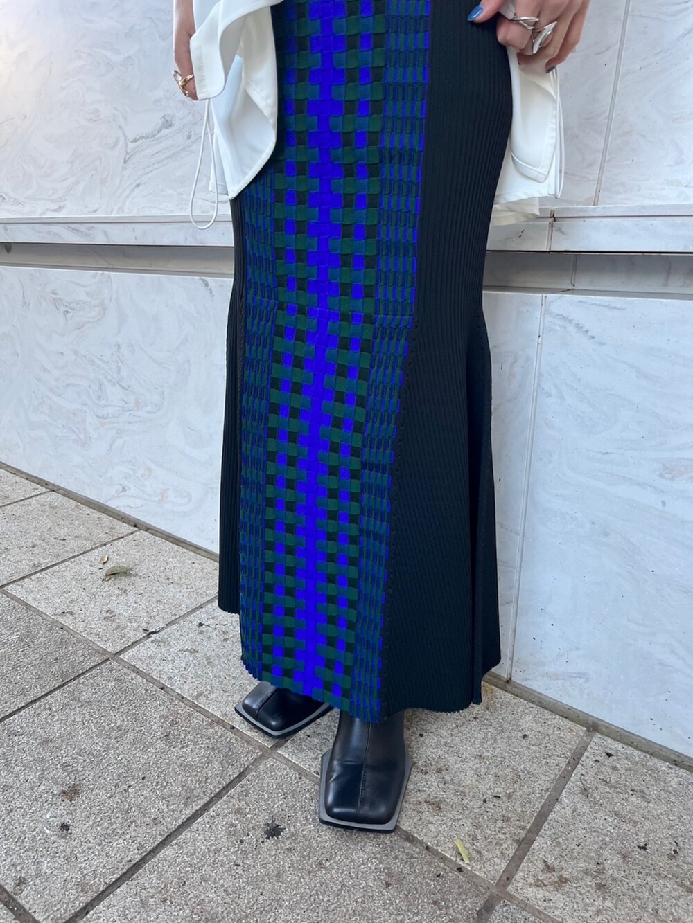 ホワイト系のタンクトップ、ブラック系のニット/セーター、ブラック系のスカートを着用したレディースの春コーディネートの7枚目の写真