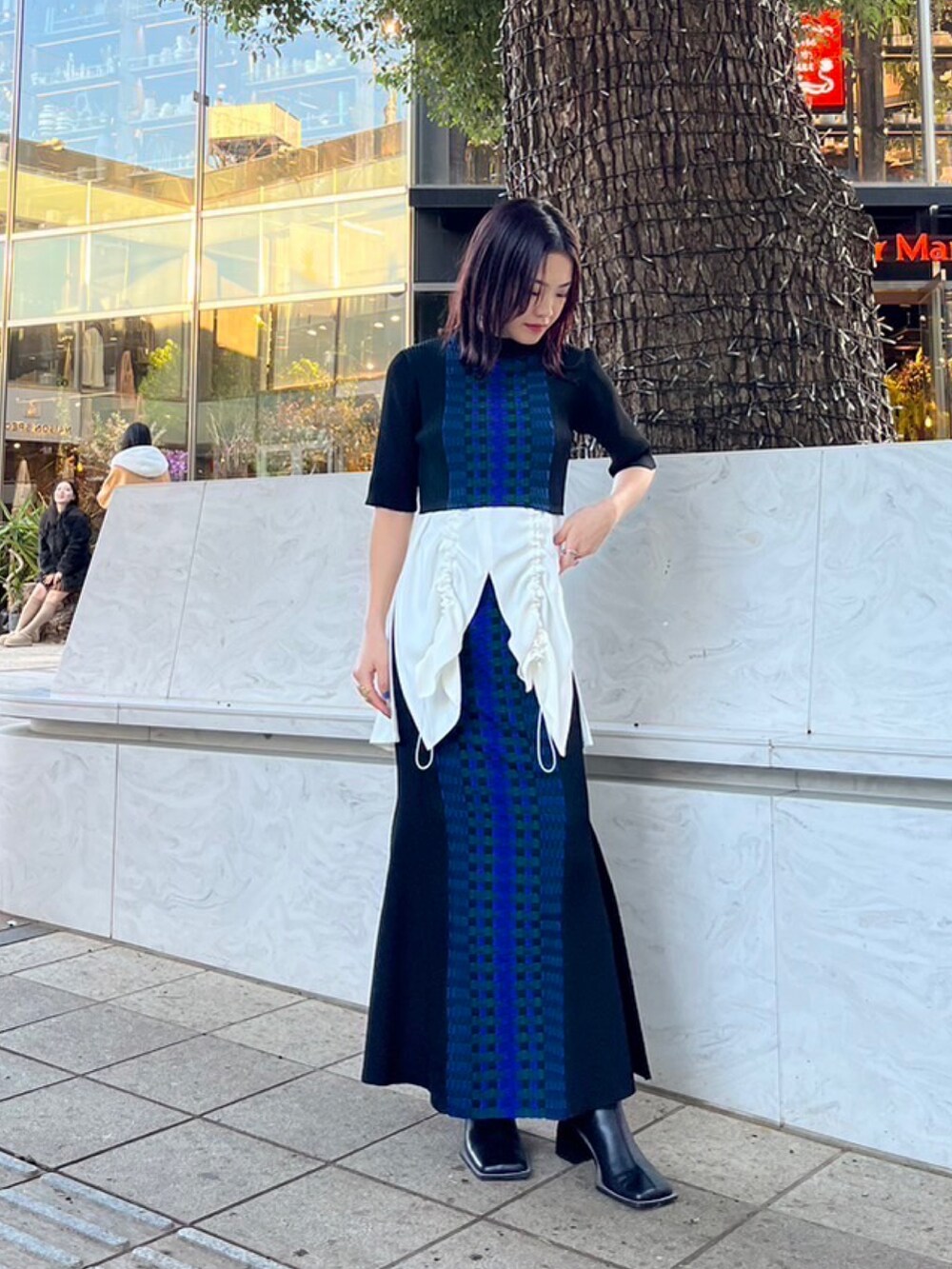 ホワイト系のタンクトップ、ブラック系のニット/セーター、ブラック系のスカートを着用したレディースの春コーディネートの2枚目の写真