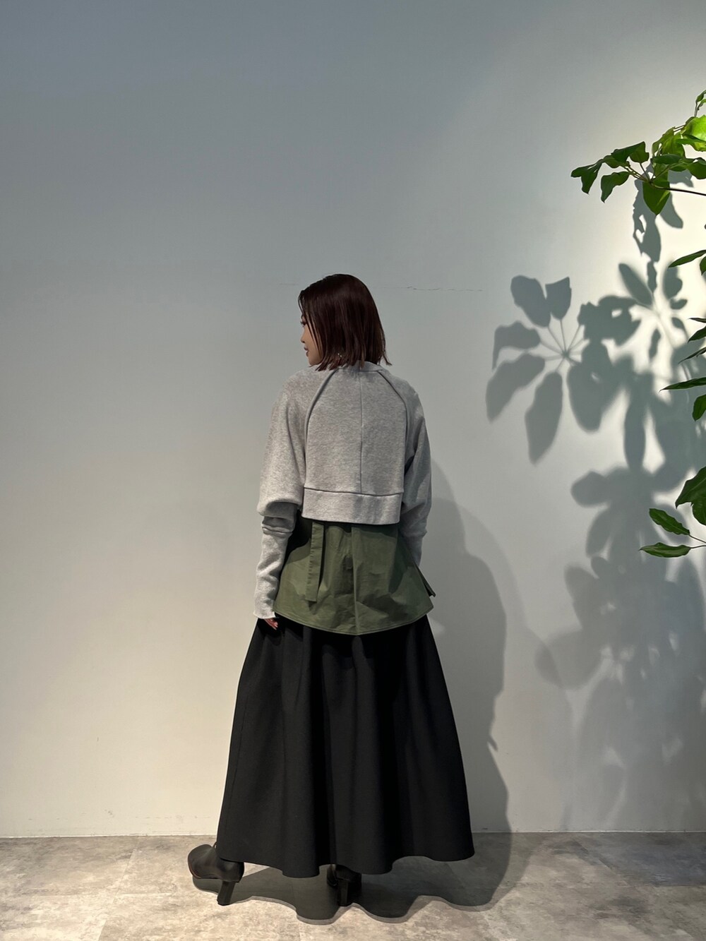 ブラック系のスカート、グリーン系のキャミソール、ブラック系のパンプスを着用したレディースの冬コーディネートの2枚目の写真