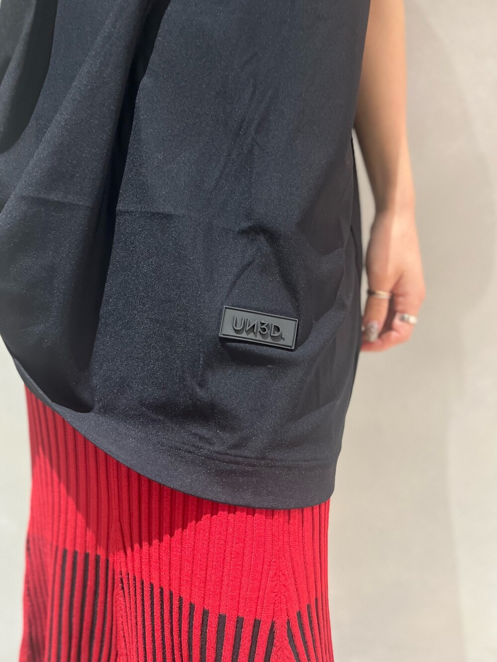 レッド系のスカート、ブラック系のTシャツ/カットソー、ブラック系のサンダルを着用したレディースの夏コーディネートの7枚目の写真