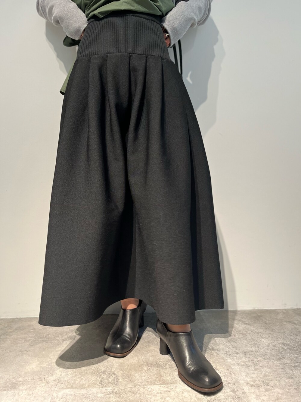 ブラック系のスカート、グリーン系のキャミソール、ブラック系のパンプスを着用したレディースの冬コーディネートの7枚目の写真