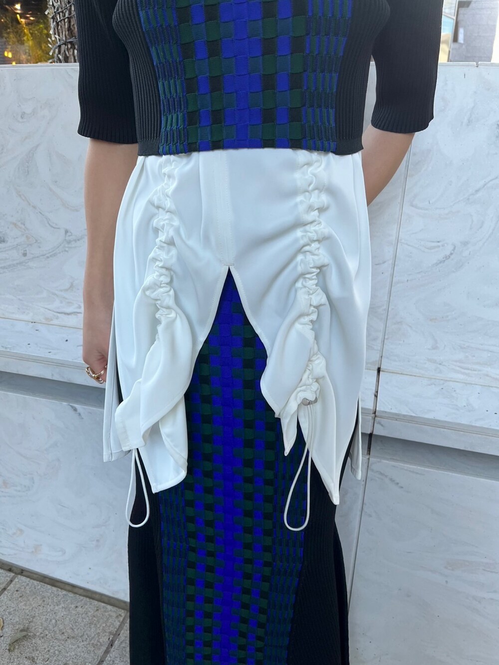 ホワイト系のタンクトップ、ブラック系のニット/セーター、ブラック系のスカートを着用したレディースの春コーディネートの6枚目の写真