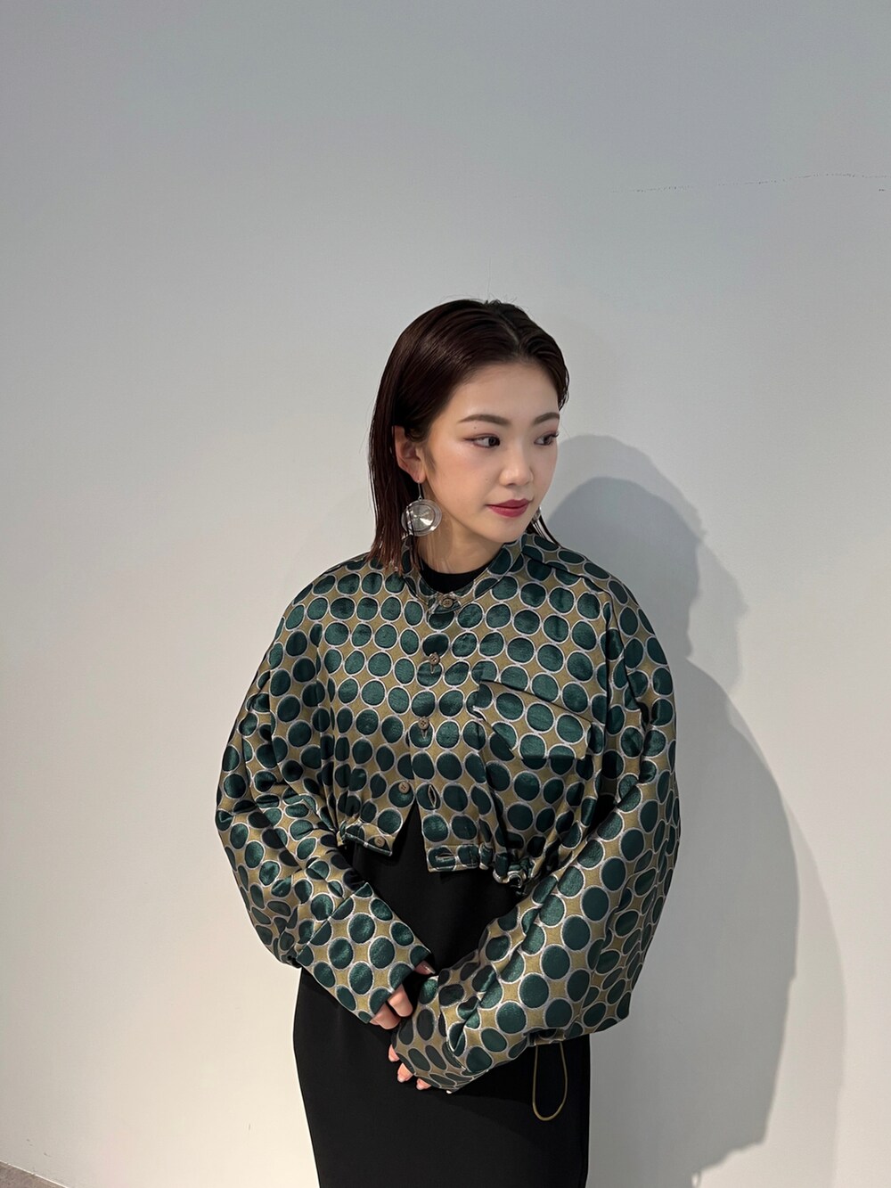 グリーン系のブルゾン、ブラック系のワンピース、グレー系のブーツを着用したレディースの秋コーディネートの2枚目の写真