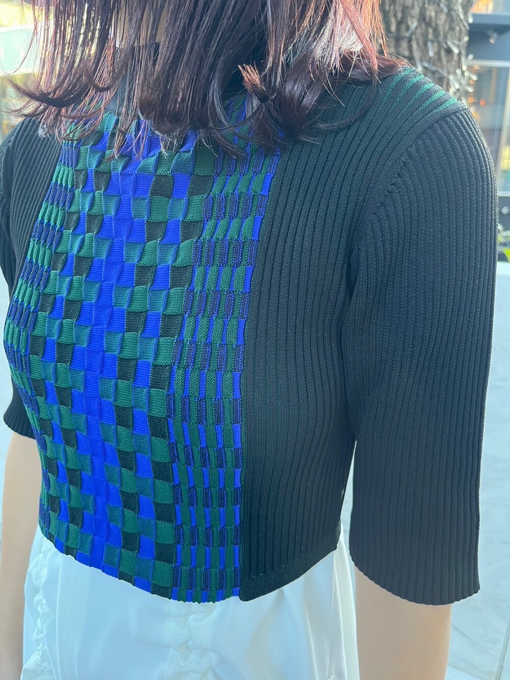 ホワイト系のタンクトップ、ブラック系のニット/セーター、ブラック系のスカートを着用したレディースの春コーディネートの4枚目の写真