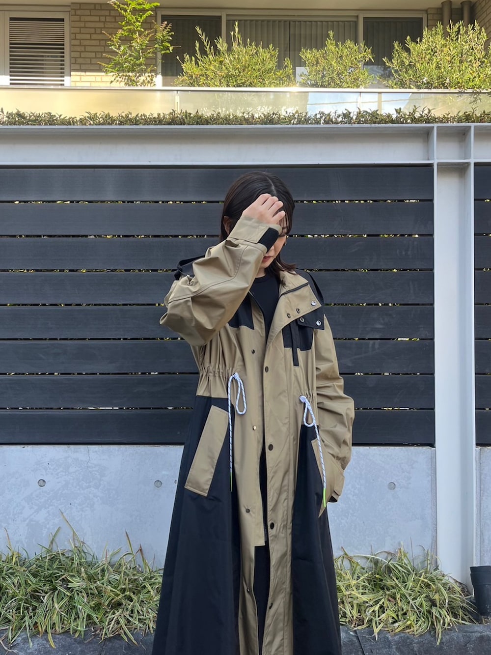 ベージュ系のマウンテンパーカー、ブラック系のワンピース、シルバー系のイヤリングを着用したレディースの冬コーディネートの3枚目の写真