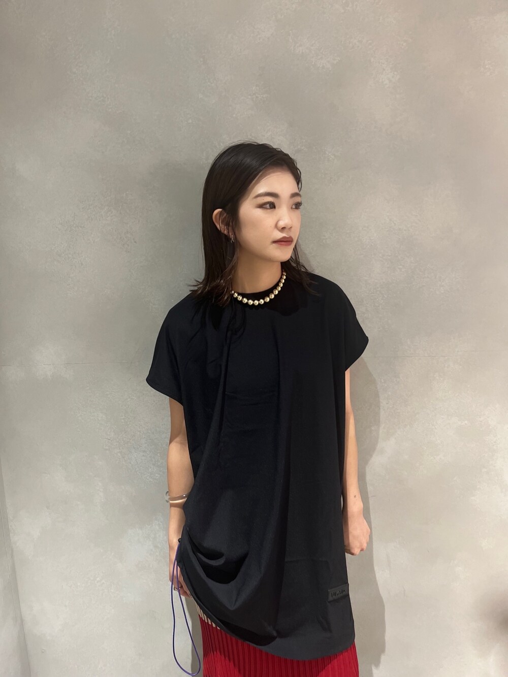 レッド系のスカート、ブラック系のTシャツ/カットソー、ブラック系のサンダルを着用したレディースの夏コーディネートの4枚目の写真