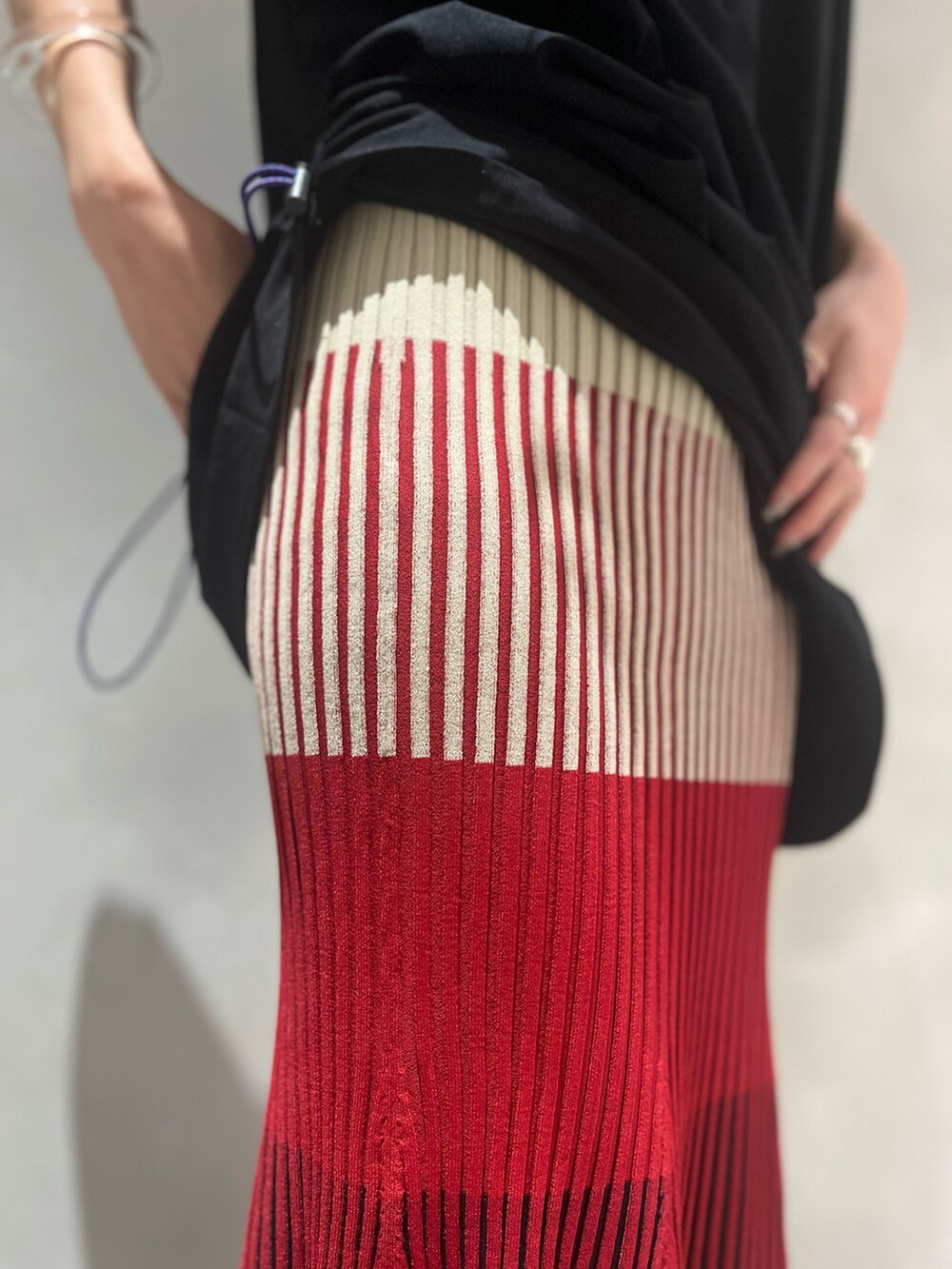 レッド系のスカート、ブラック系のTシャツ/カットソー、ブラック系のサンダルを着用したレディースの夏コーディネートの9枚目の写真