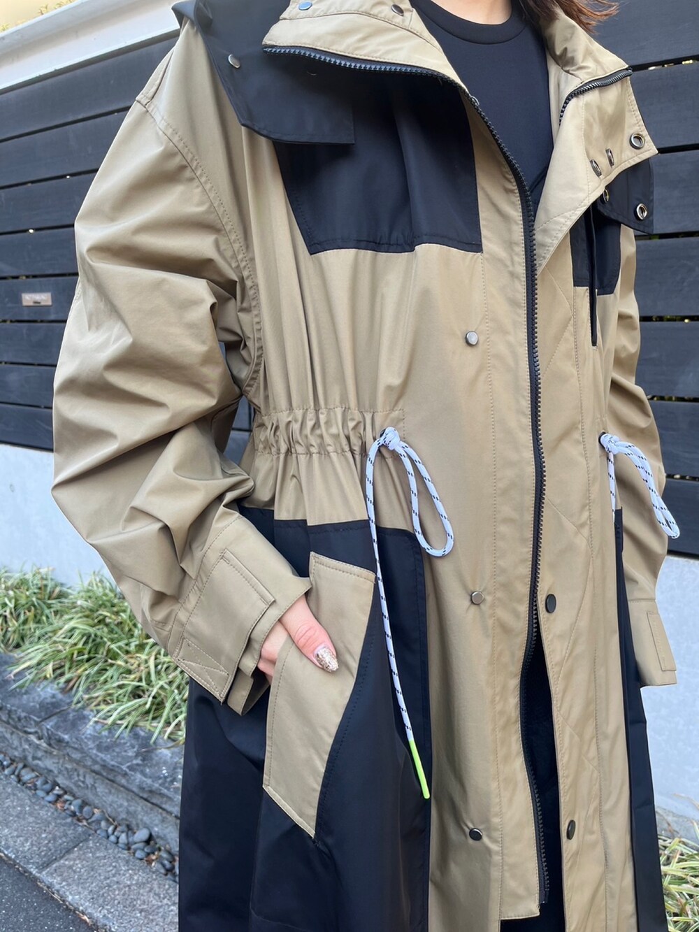 ベージュ系のマウンテンパーカー、ブラック系のワンピース、シルバー系のイヤリングを着用したレディースの冬コーディネートの5枚目の写真