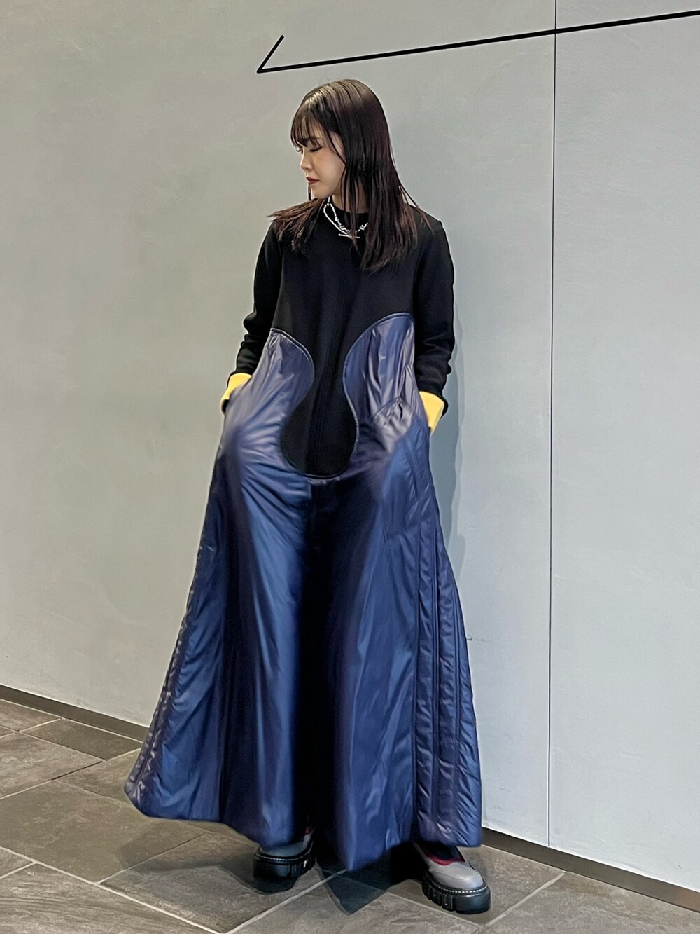 グレー系のブーツ、ブルー系のワンピース、シルバー系のネックレスを着用したレディースの秋コーディネートの2枚目の写真