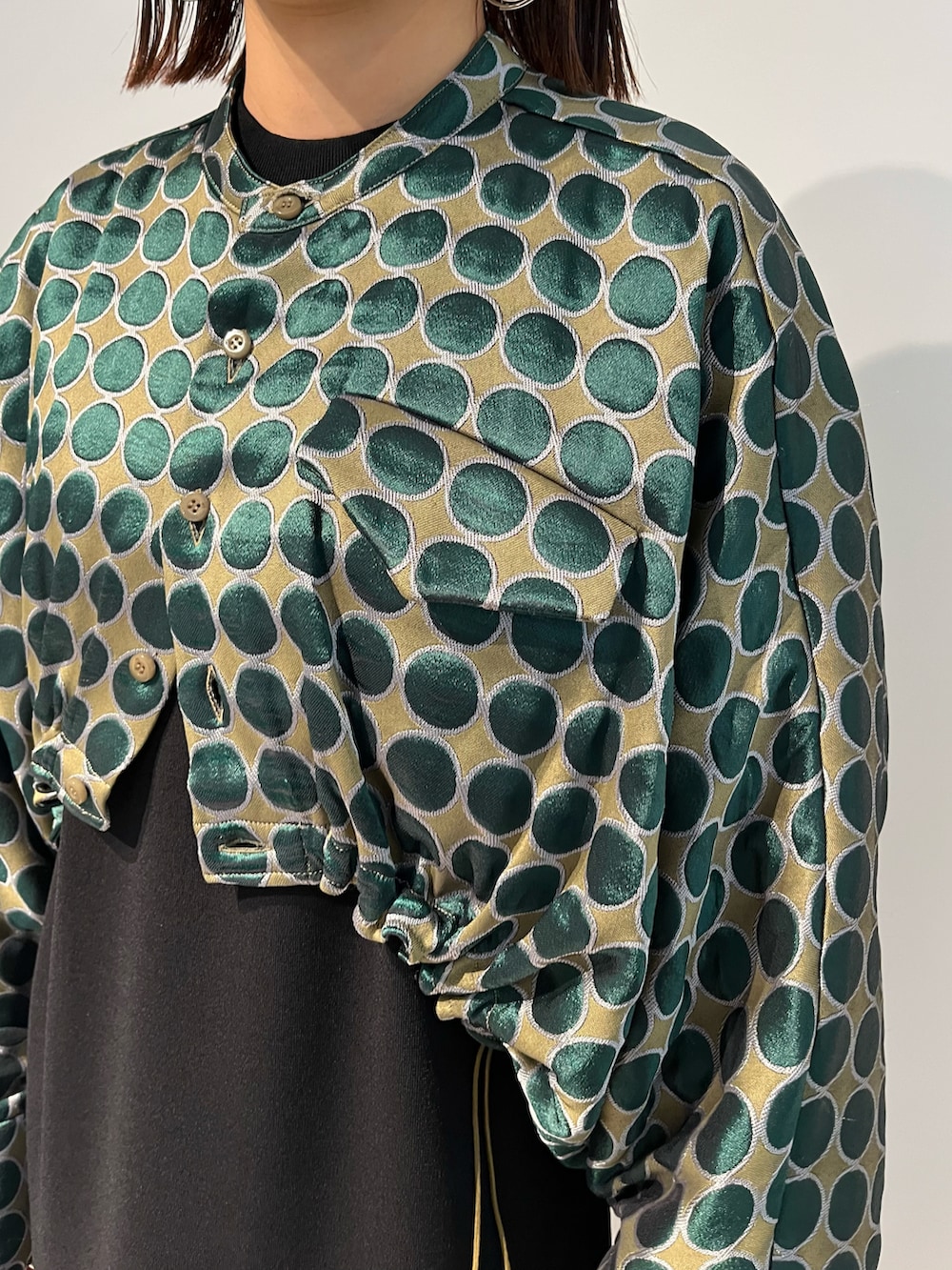 グリーン系のブルゾン、ブラック系のワンピース、グレー系のブーツを着用したレディースの秋コーディネートの3枚目の写真