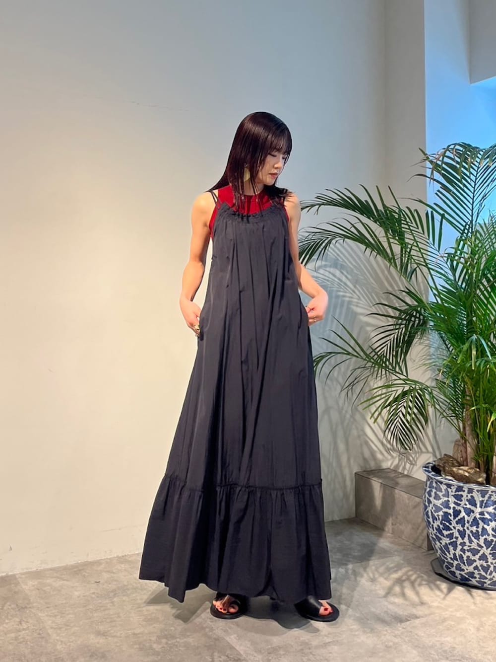 レッド系のタンクトップ、ブラック系のサンダル、ブラック系のスーツケース/キャリーバッグを着用したレディースの春コーディネートの2枚目の写真