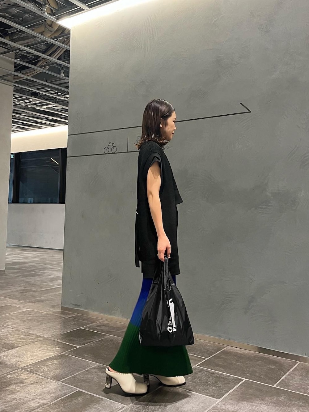 ブラック系のエコバッグ/サブバッグ、ブルー系のスカート、ブラック系のベストを着用したレディースの夏コーディネートの2枚目の写真