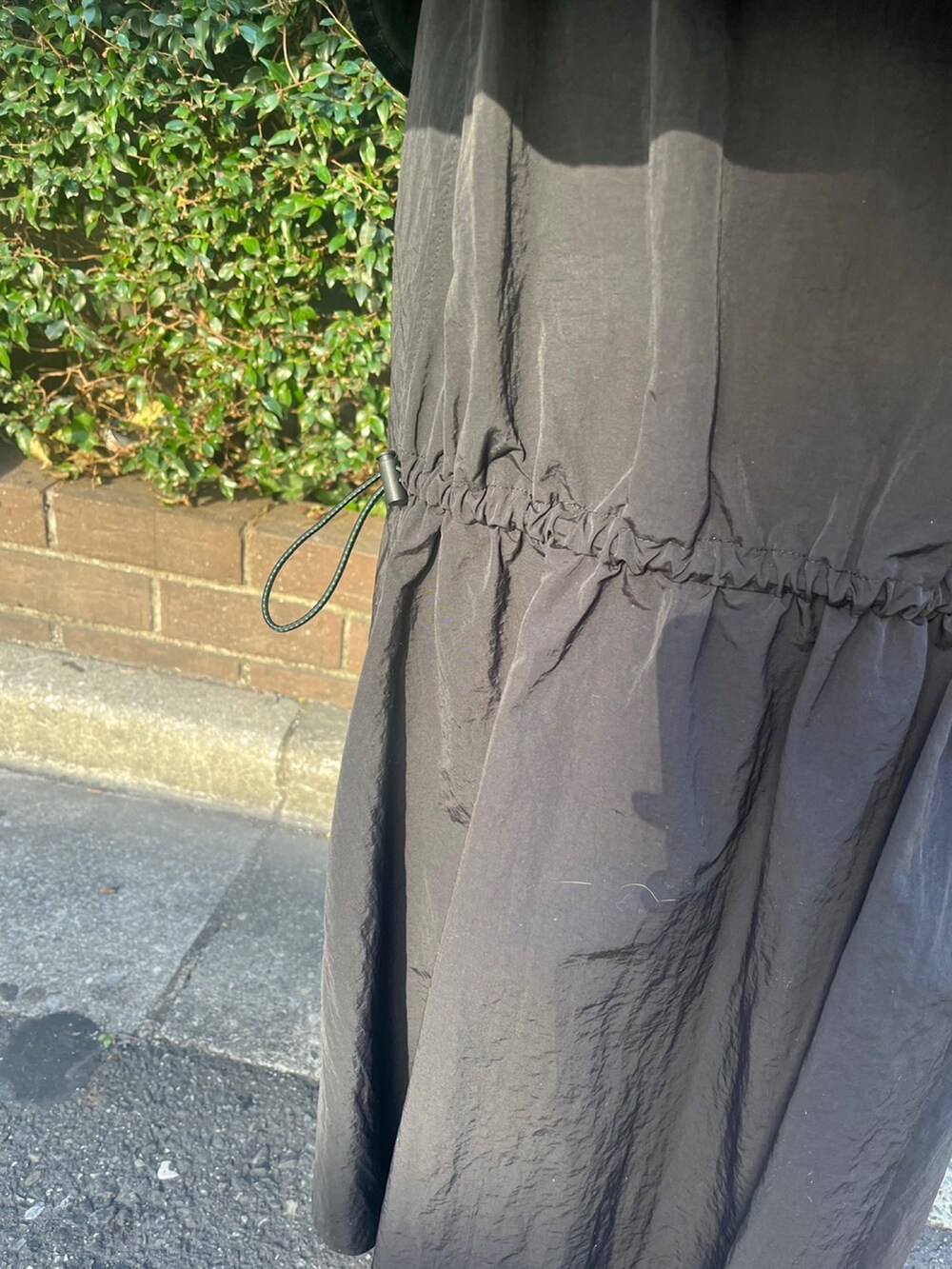 ブラック系のマウンテンパーカー、ブラック系のスカート、シルバー系のブーツを着用したレディースの冬コーディネートの10枚目の写真