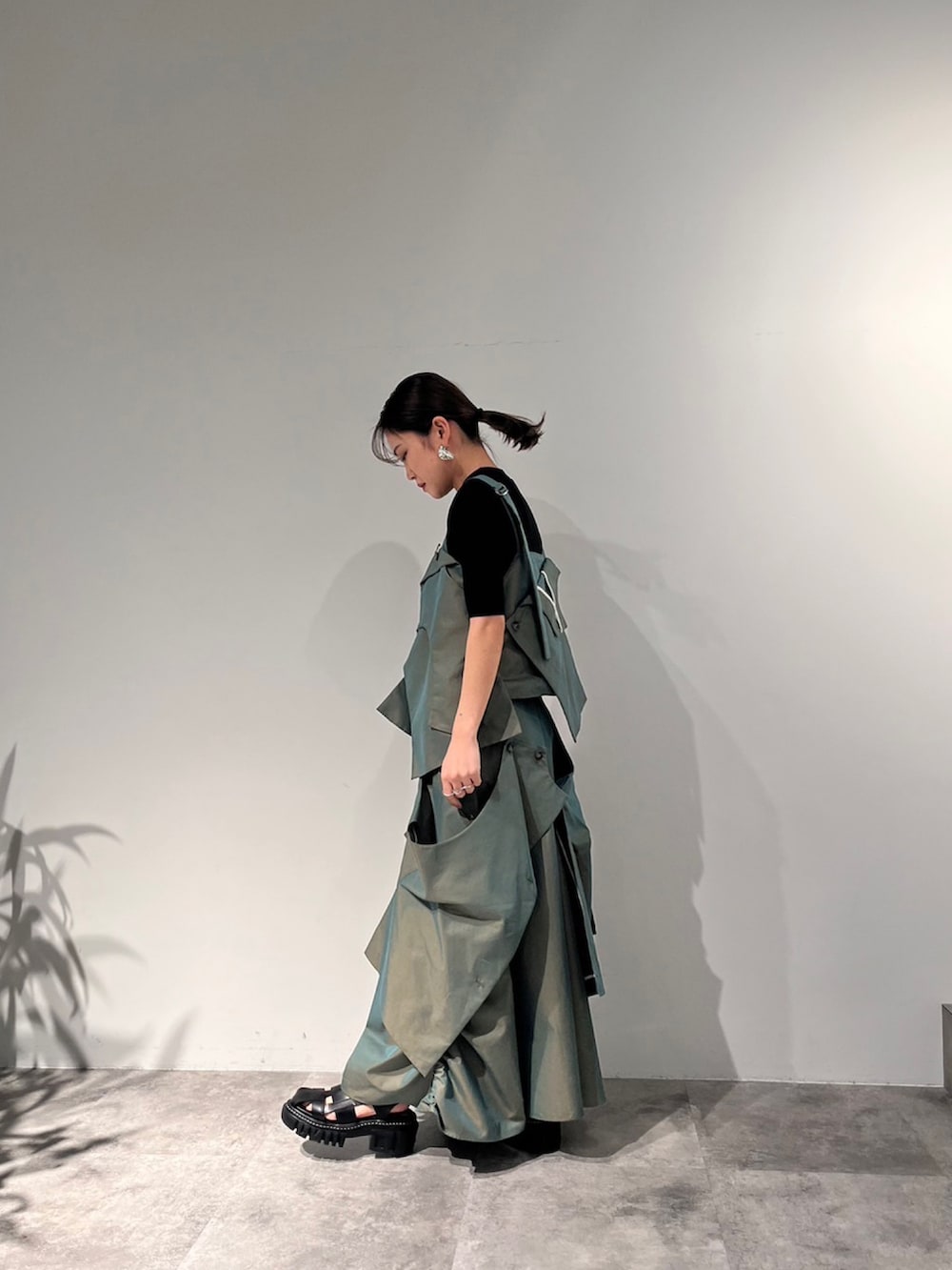 グリーン系のスカート、ベージュ系のキャミソール、ブラック系のサンダルを着用したレディースの冬コーディネートの3枚目の写真