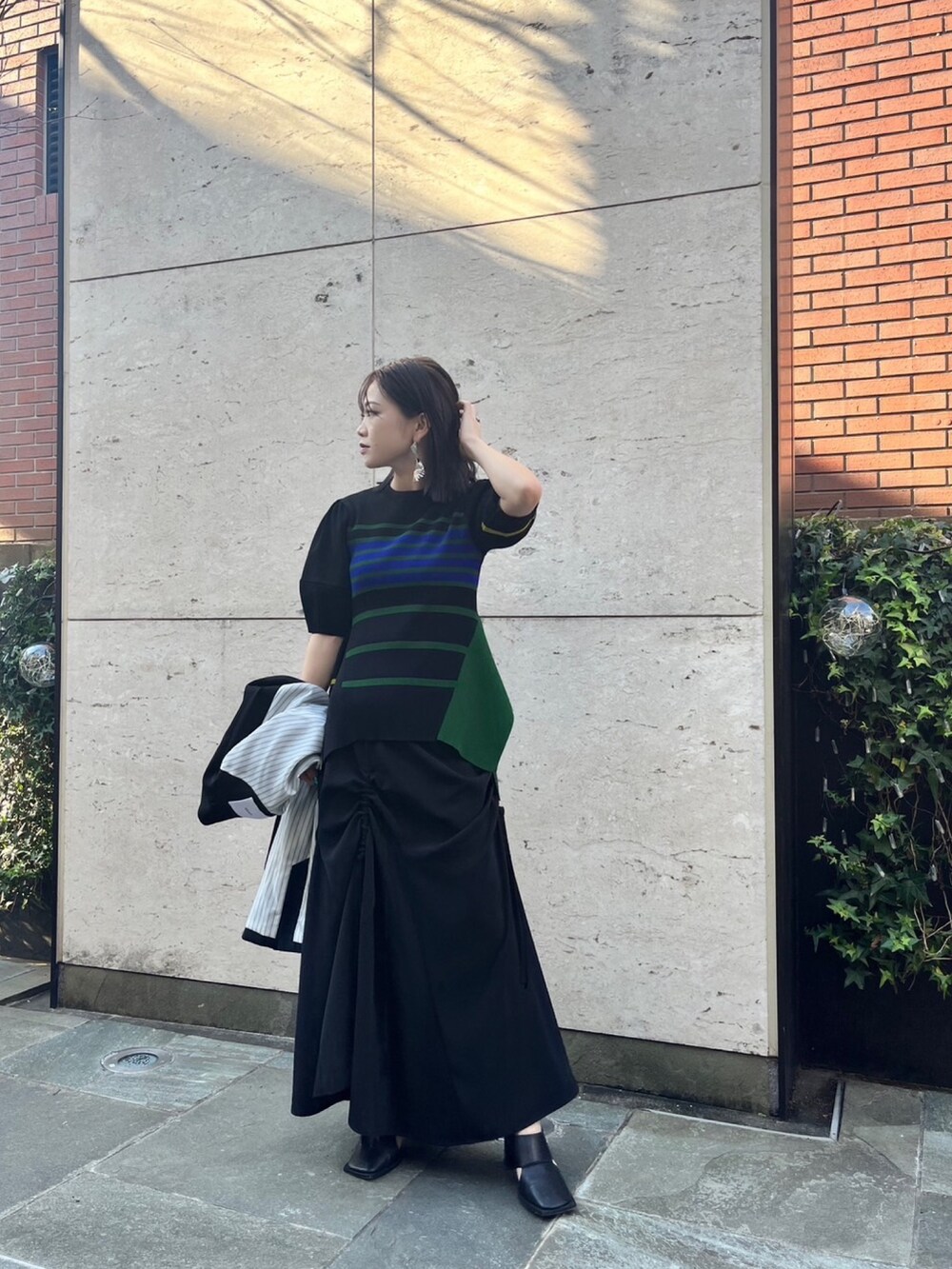 ブラック系のスカート、ブラック系のパンプス、ブラック系のテーラードジャケットを着用したレディースの冬コーディネートの4枚目の写真