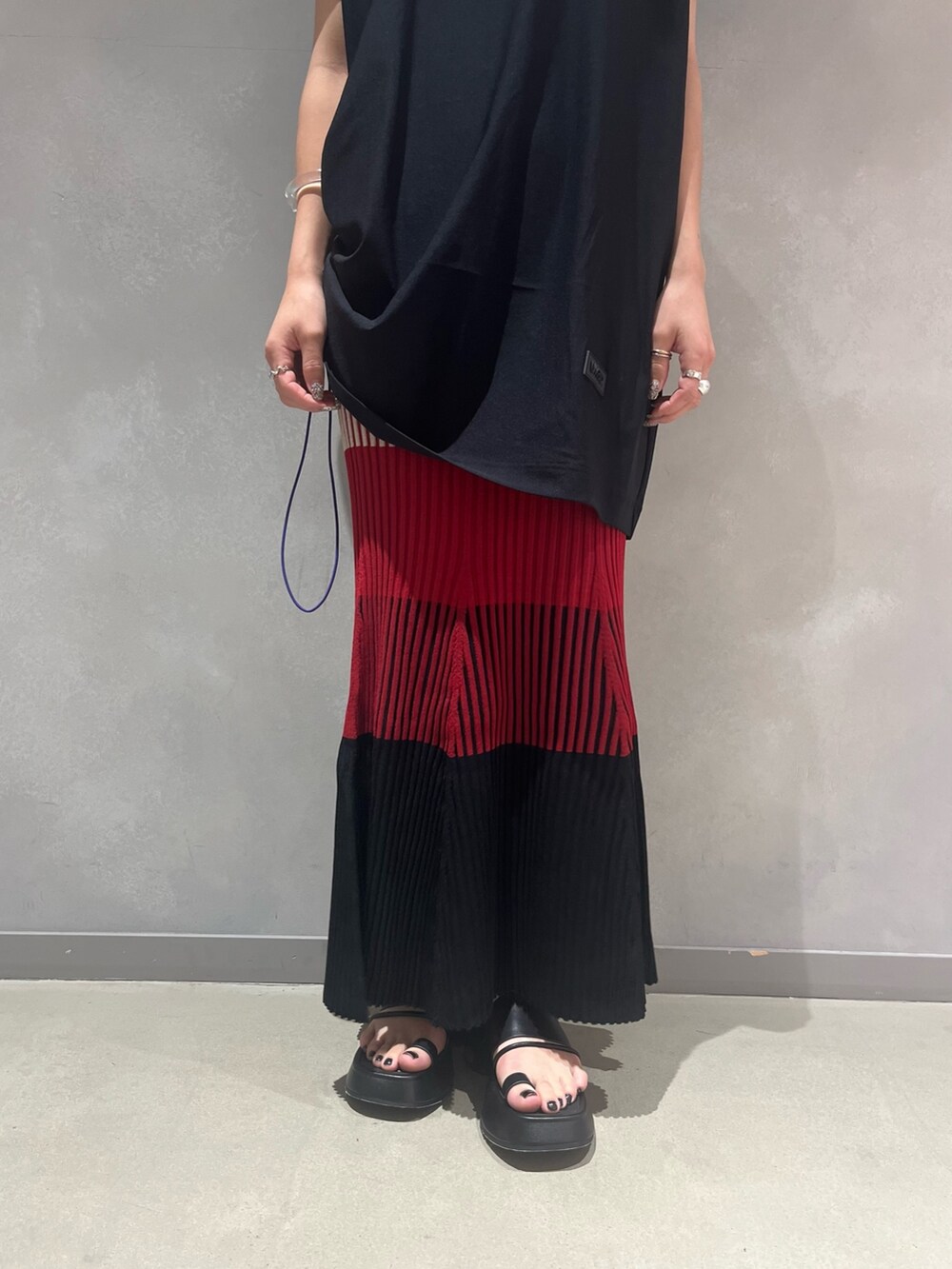 レッド系のスカート、ブラック系のTシャツ/カットソー、ブラック系のサンダルを着用したレディースの夏コーディネートの8枚目の写真