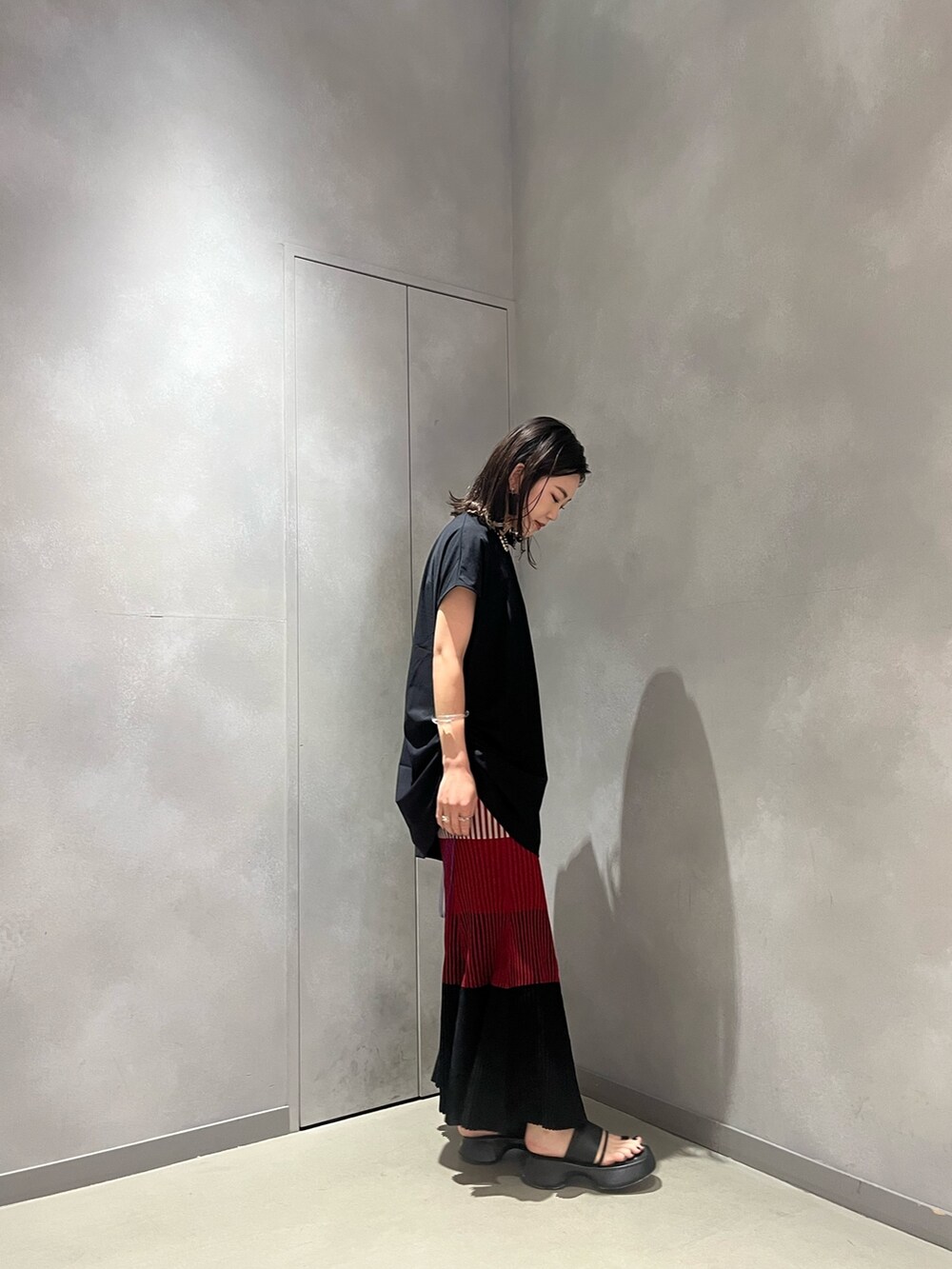 レッド系のスカート、ブラック系のTシャツ/カットソー、ブラック系のサンダルを着用したレディースの夏コーディネートの3枚目の写真