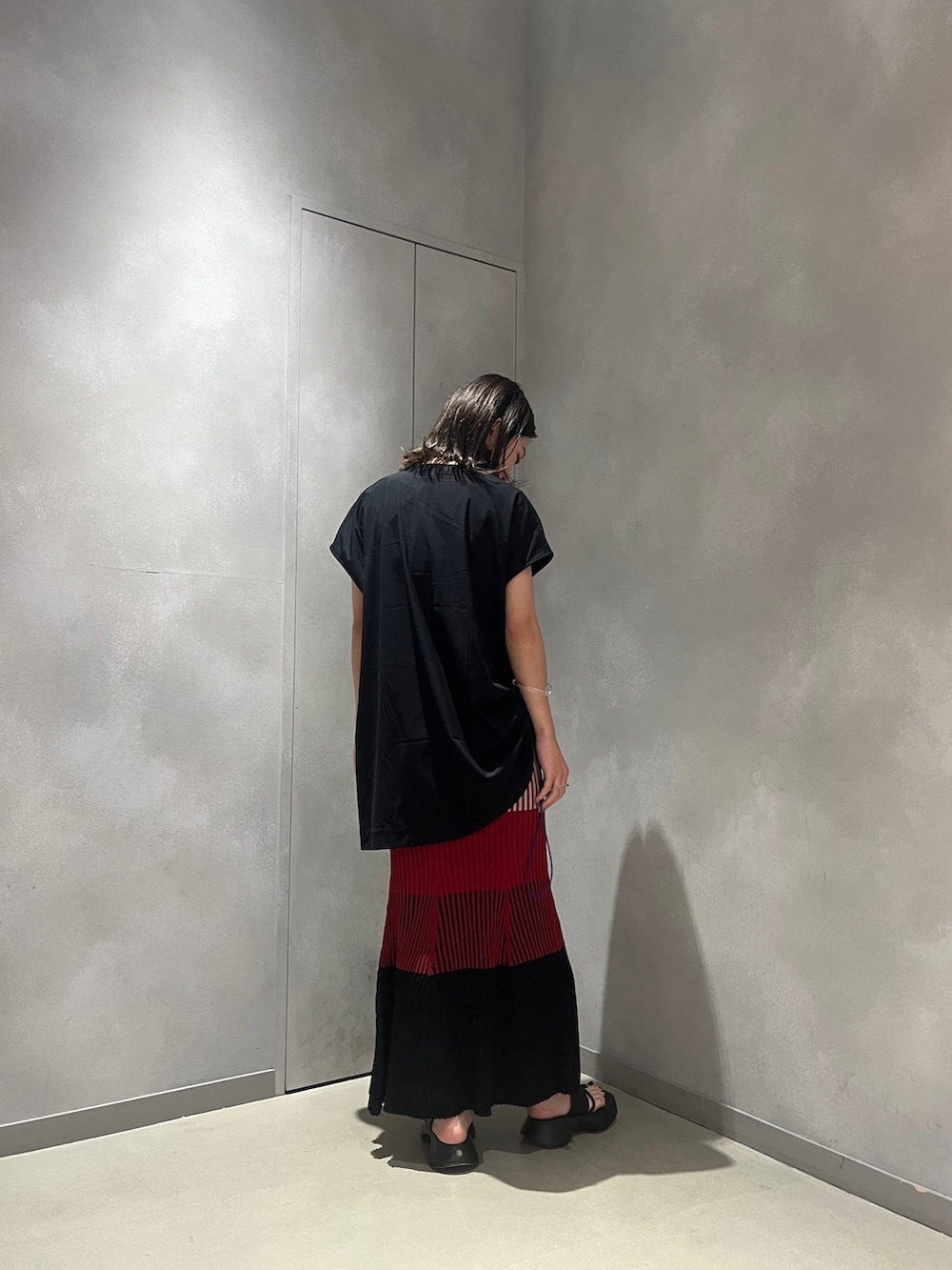 レッド系のスカート、ブラック系のTシャツ/カットソー、ブラック系のサンダルを着用したレディースの夏コーディネートの2枚目の写真