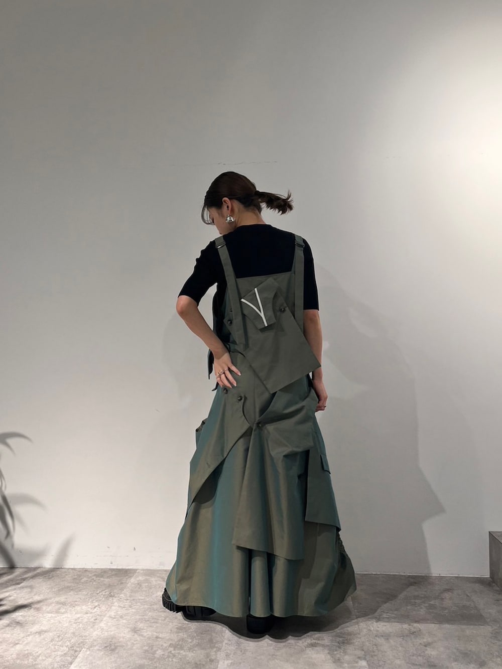 グリーン系のスカート、ベージュ系のキャミソール、ブラック系のサンダルを着用したレディースの冬コーディネートの2枚目の写真