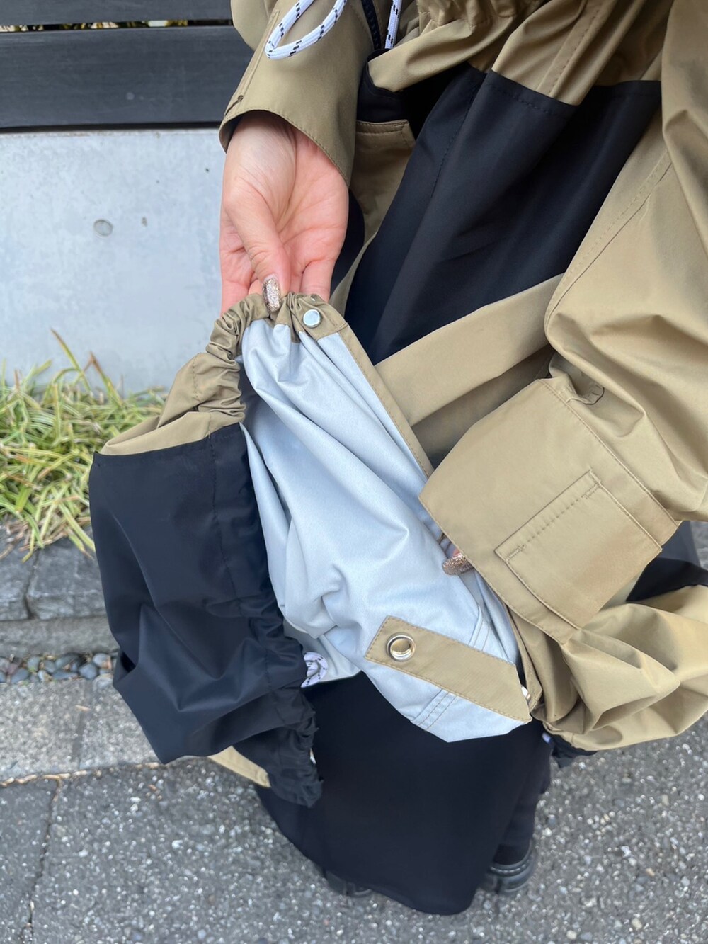 ベージュ系のマウンテンパーカー、ブラック系のワンピース、シルバー系のイヤリングを着用したレディースの冬コーディネートの6枚目の写真