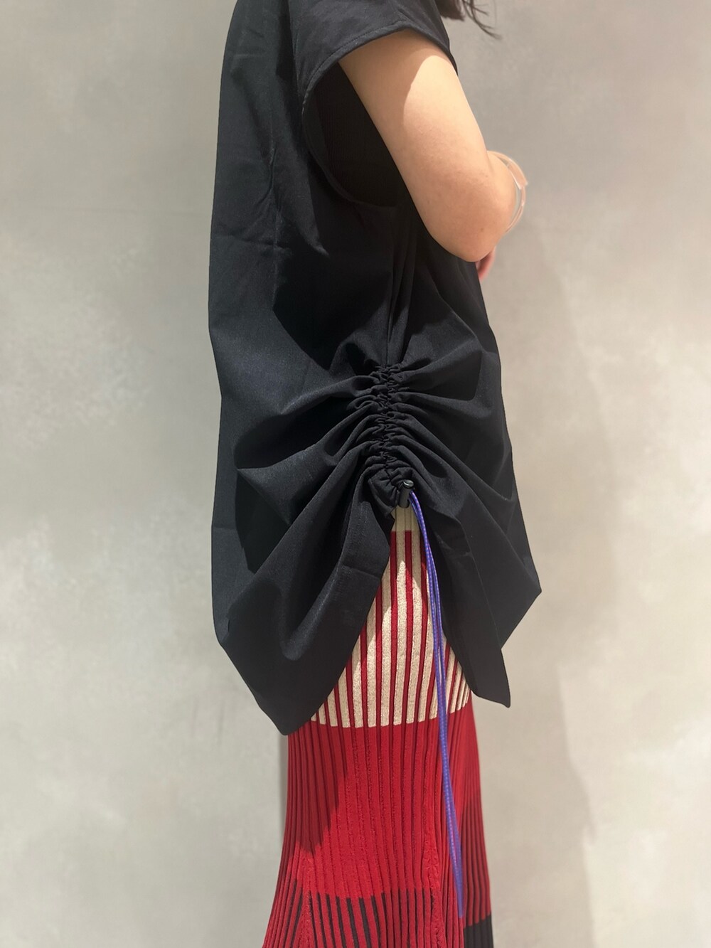 レッド系のスカート、ブラック系のTシャツ/カットソー、ブラック系のサンダルを着用したレディースの夏コーディネートの6枚目の写真