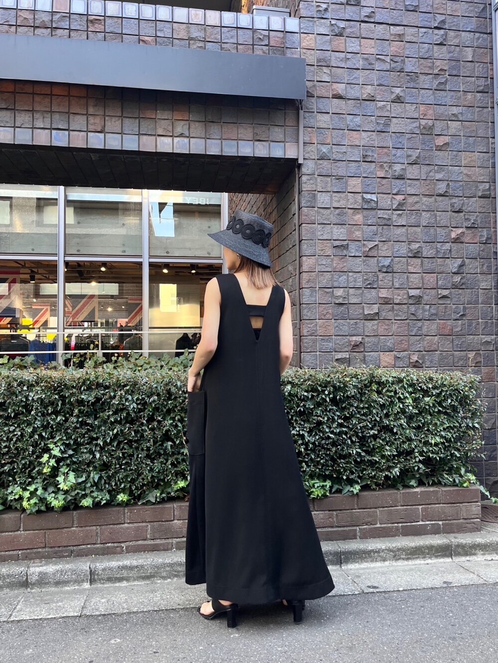 ブラック系のワンピース、ブラック系のサンダル、ブラック系のハットを着用したレディースの春コーディネートの3枚目の写真