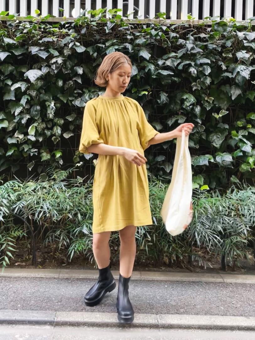 ブラック系のブーツ、イエロー系のエコバッグ/サブバッグ、グリーン系のワンピースを着用したレディースの春コーディネートの3枚目の写真