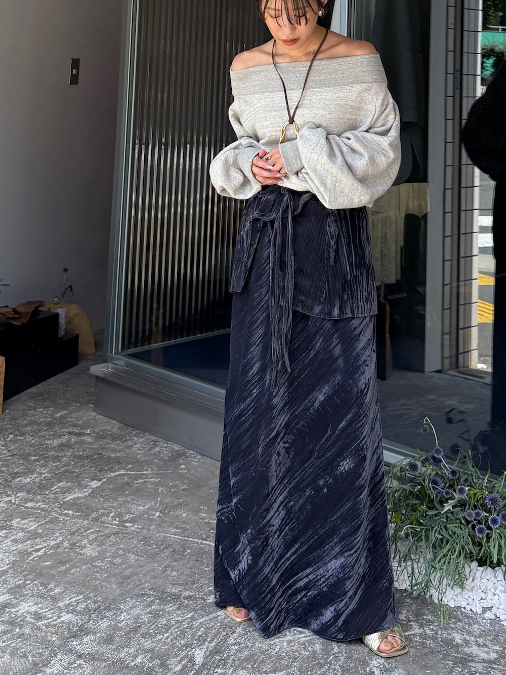 グレー系のスウェット、ブラック系のスカート、ゴールド系のネックレスを着用したレディースの夏コーディネートの2枚目の写真