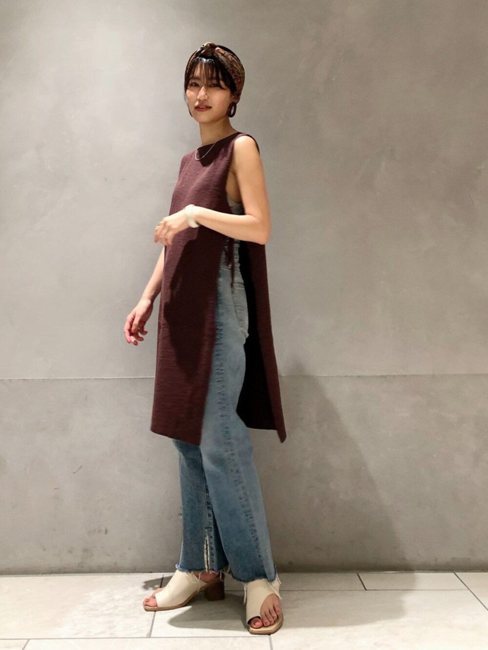 ブルー系のデニムパンツ、ブラウン系のベストを着用したレディースの春コーディネートの3枚目の写真