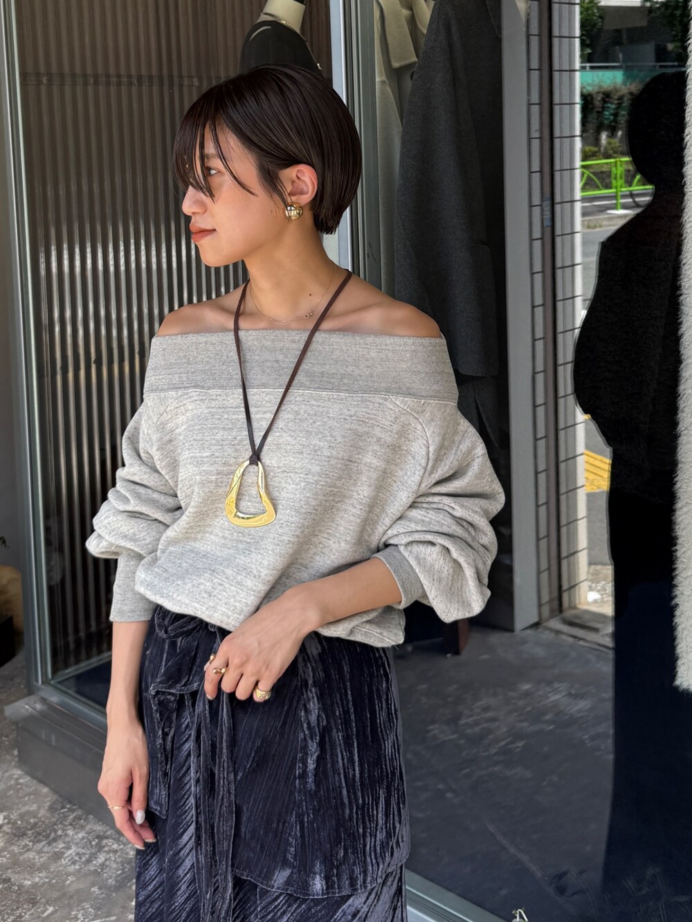 グレー系のスウェット、ブラック系のスカート、ゴールド系のネックレスを着用したレディースの夏コーディネートの4枚目の写真