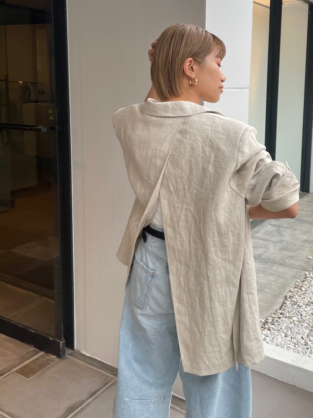 ベージュ系のテーラードジャケット、ホワイト系のタンクトップを着用したレディースの春コーディネートの6枚目の写真